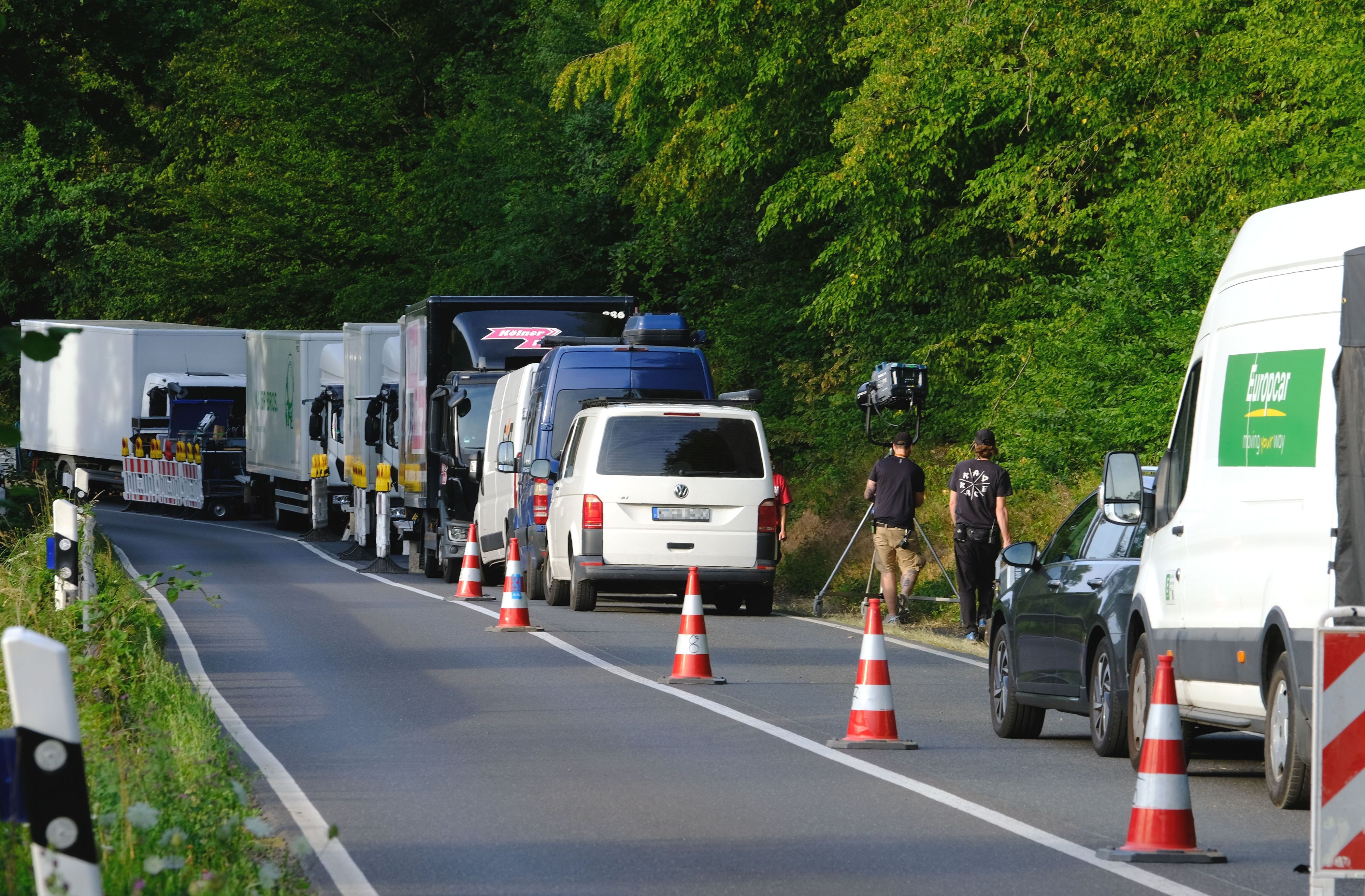 Auf einem abgesperrten Fahrstreifen der L61 bei Katzvey stehen Lastwagen eeiner Filmproduktionsgesellschaft. Zwei Männer schieben einen Scheinwerfer über den Gehsteig.