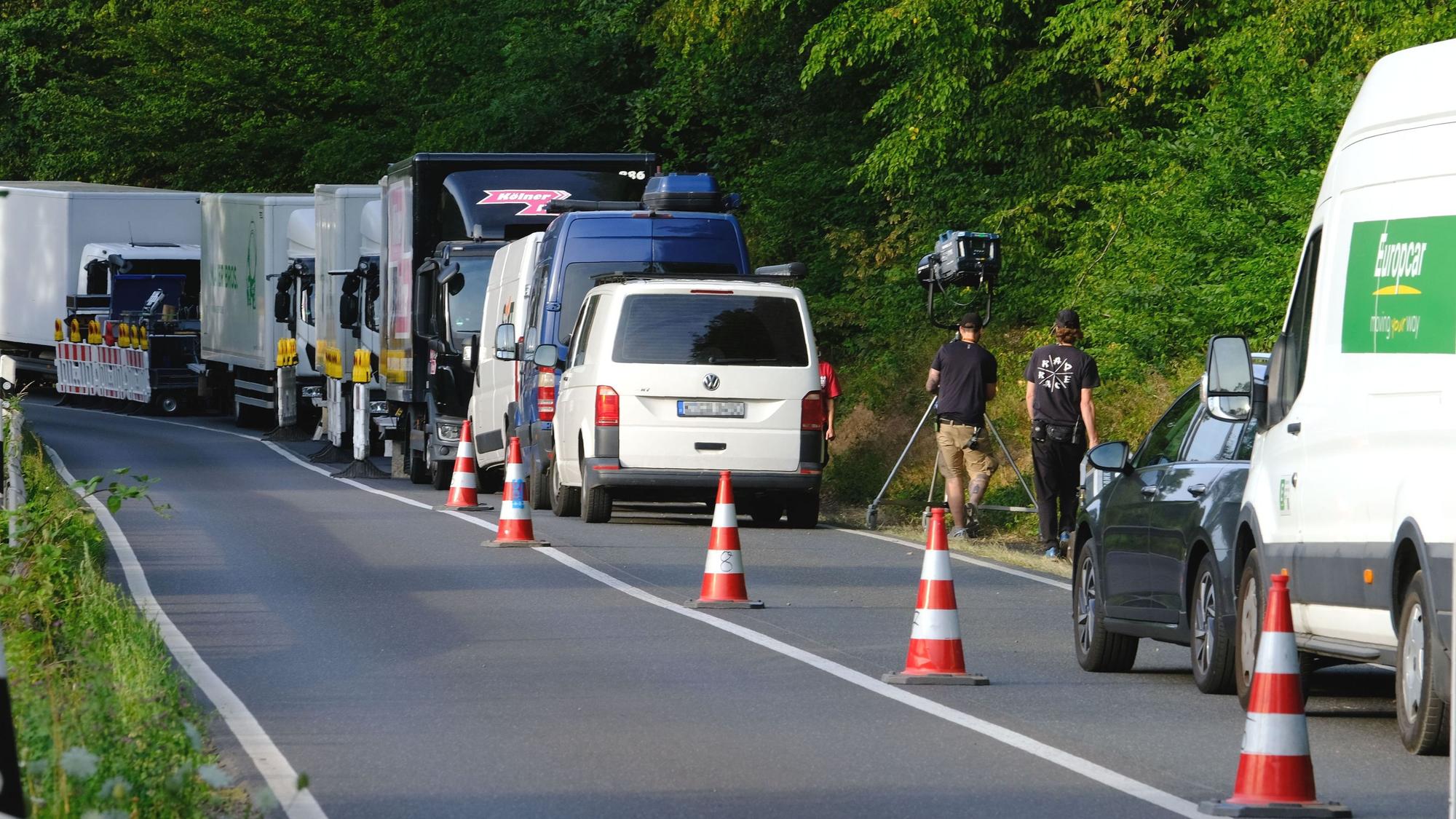 Auf einem abgesperrten Fahrstreifen der L61 bei Katzvey stehen Lastwagen eeiner Filmproduktionsgesellschaft. Zwei Männer schieben einen Scheinwerfer über den Gehsteig.