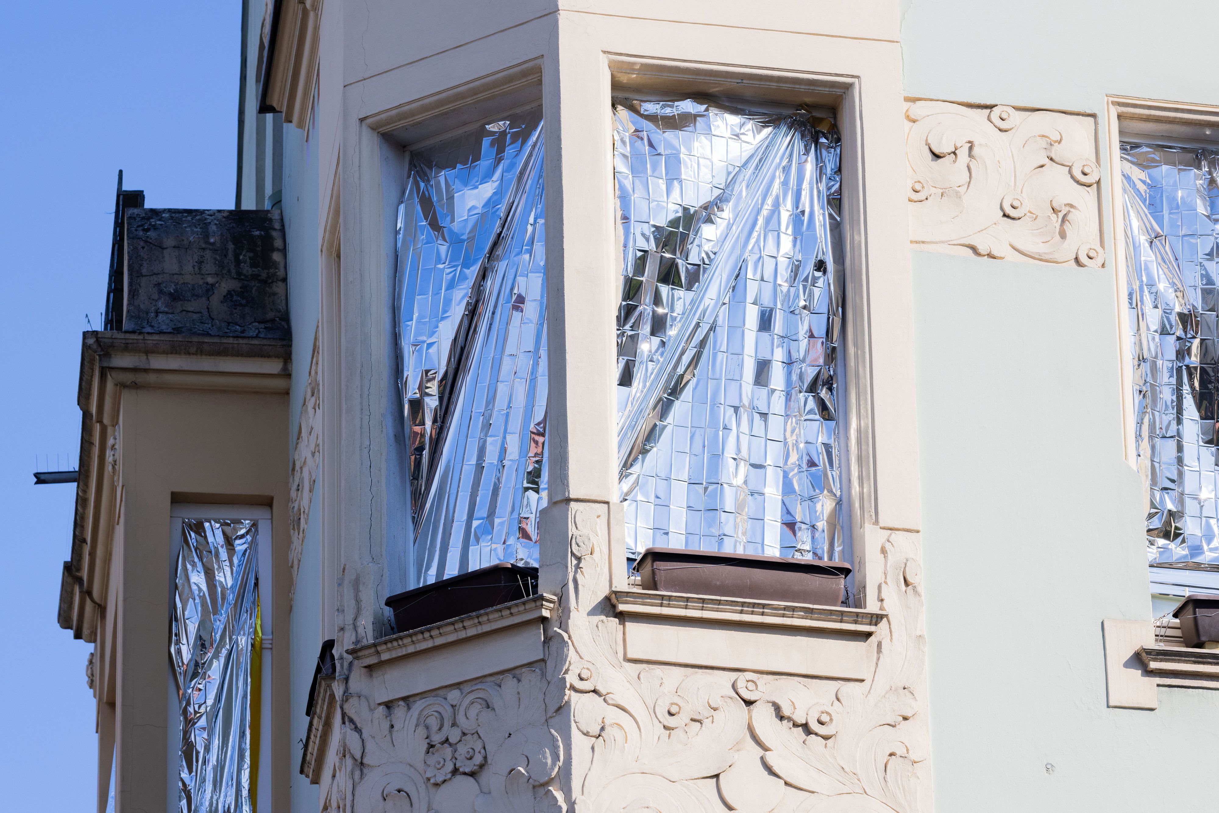 Menschen schützen ihre Wohnungen in Köln mit Rettungsdecken, die mit Aluminium beschichtet sind, vor der Hitze und der Sonne.