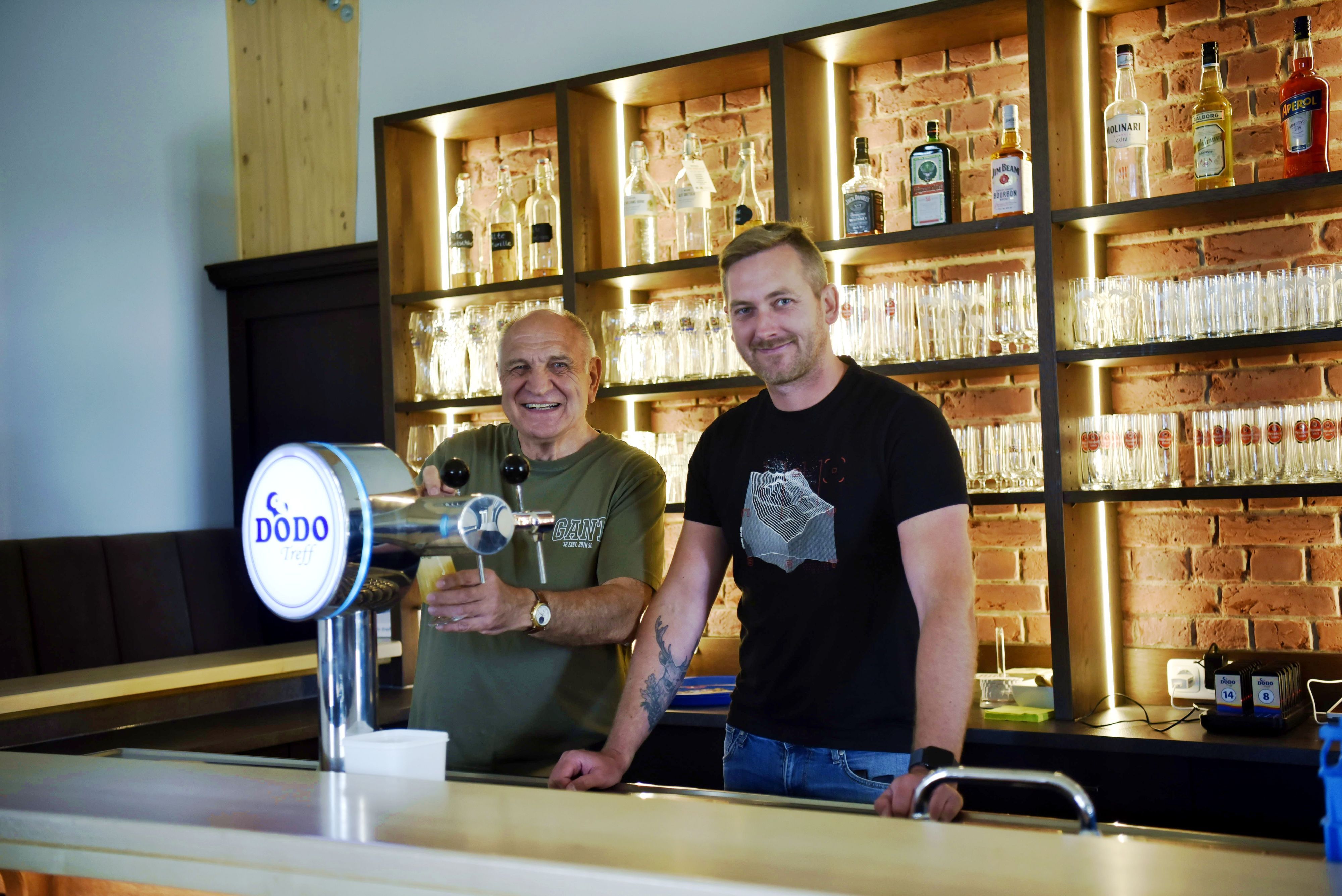 Hans-Josef Wolf und Tim Ziegler stehen an der Zapfanlage hinter der Theke des Dodo-Treffs.