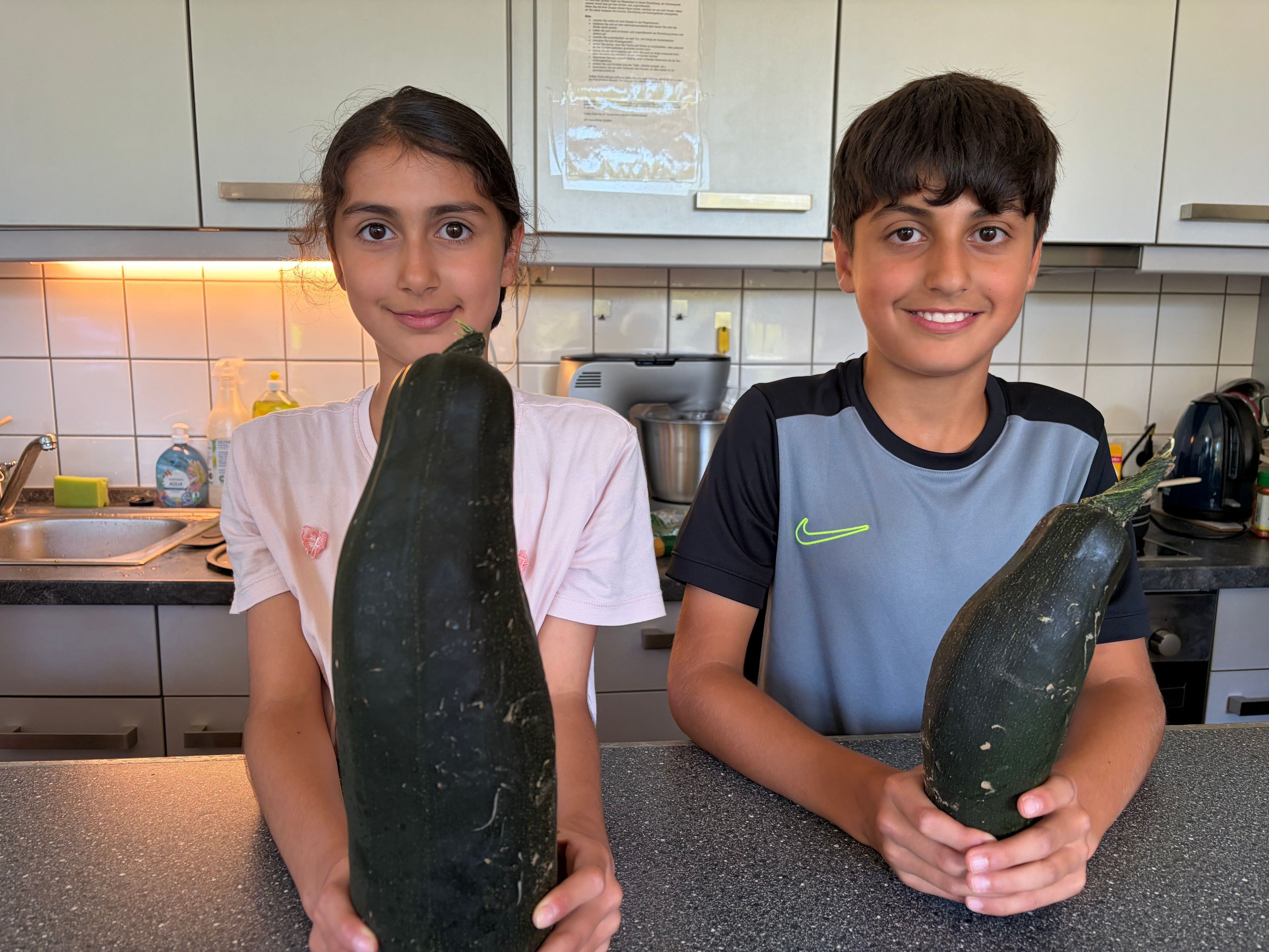 Stolz auf die eigene Ernte: Solin und Ahmed mit Zucchini aus dem Jugendhaus-Garten