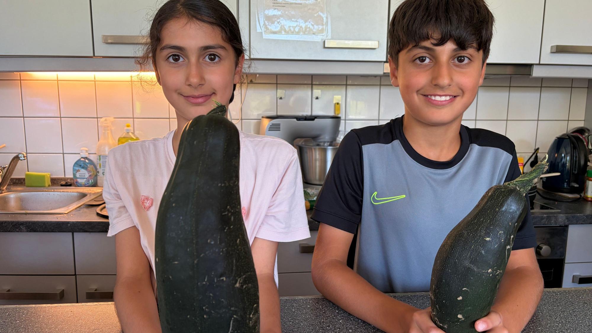 Stolz auf die eigene Ernte: Solin und Ahmed mit Zucchini aus dem Jugendhaus-Garten