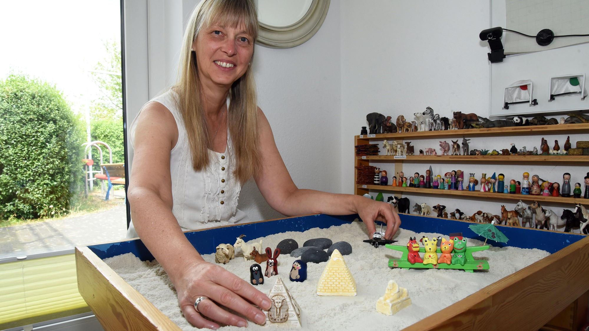Das Foto zeigt Annette Giesler mit Figuren im Sandkasten.