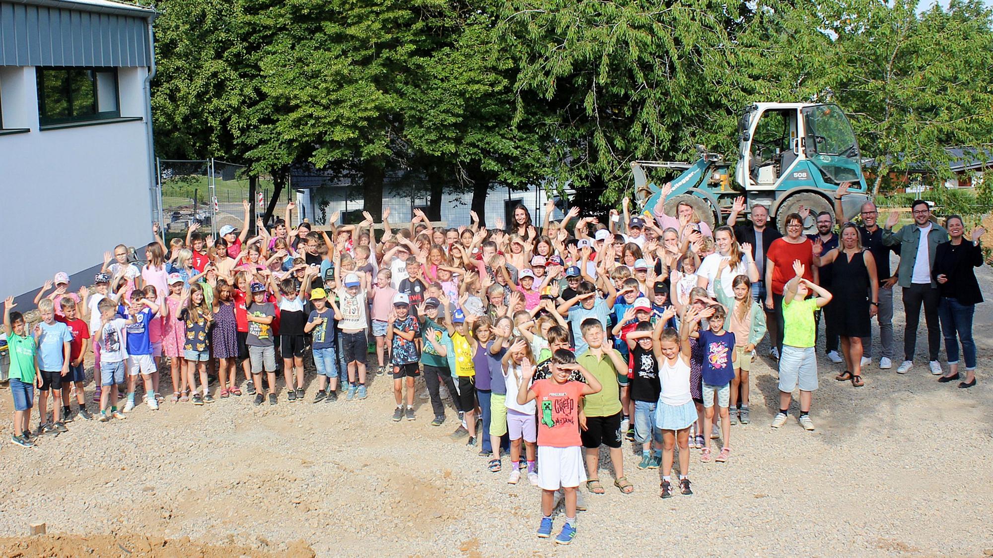 Viele Kinder und einige Erwachsene stehen auf dem Gelände, wo der Soccer-Court angelegt wird.