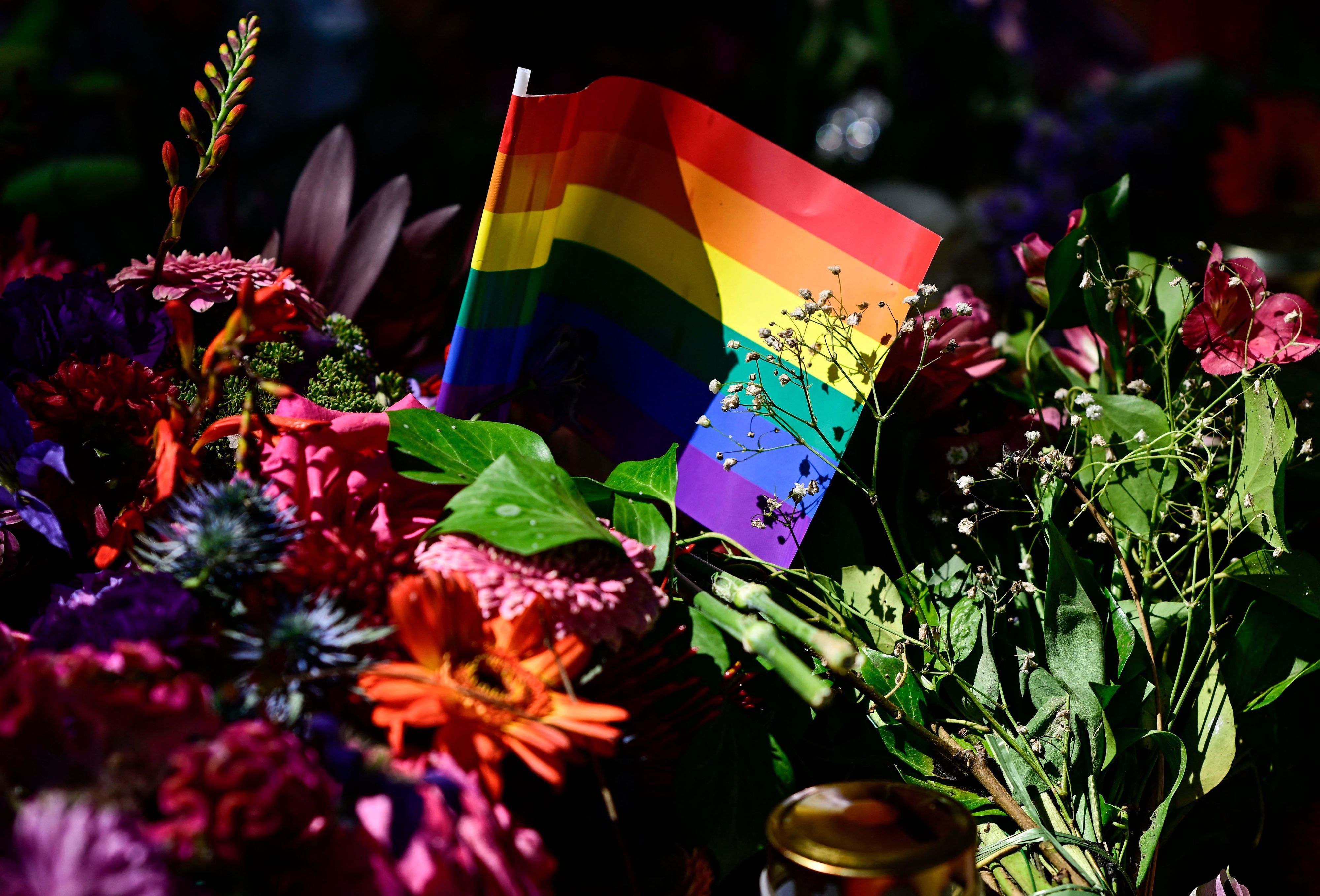 Flowers, a candle and a rainbow flag have been placed at a makeshift memorial in tribute to the victims at the Tiergarten park in Berlin on July 28, 2026, three days after a car ramming attack that killed one person and injured 29 near the Christopher Street Day (CSD) parade. German police had shot and killed the chief suspect in what officials described as a deadly Islamist attack near the Berlin Pride parade the night prior, the latest ramming assault to hit the country. The attack late on July 25 -- the first such incident to target the German capital's LGBTQ community, killed one woman and wounded 29 others. (Photo by John MACDOUGALL / AFP)