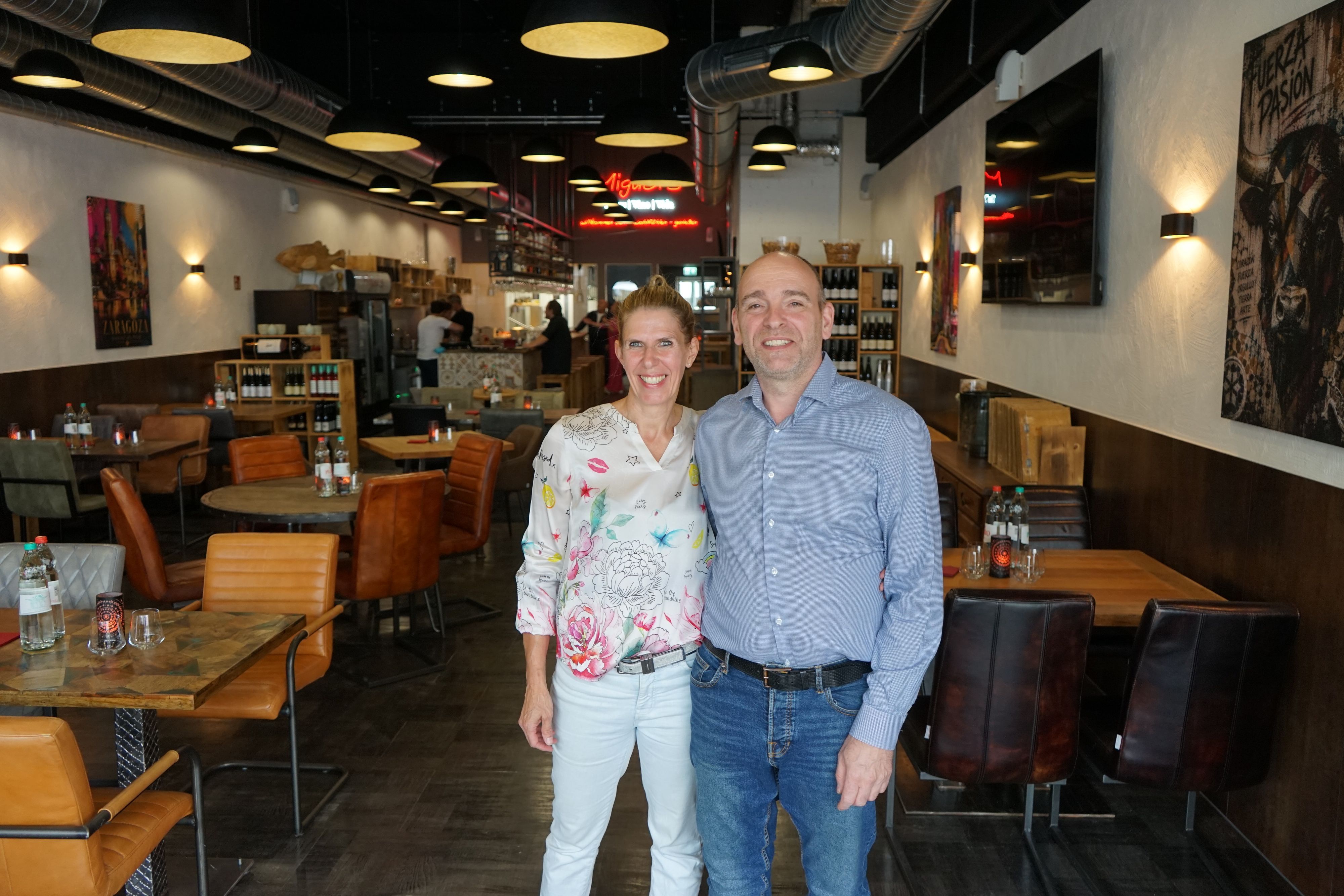Eine Frau und ein Mann stehen in einem Restaurant und lächeln.