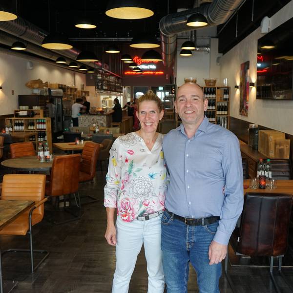 Eine Frau und ein Mann stehen in einem Restaurant und lächeln.