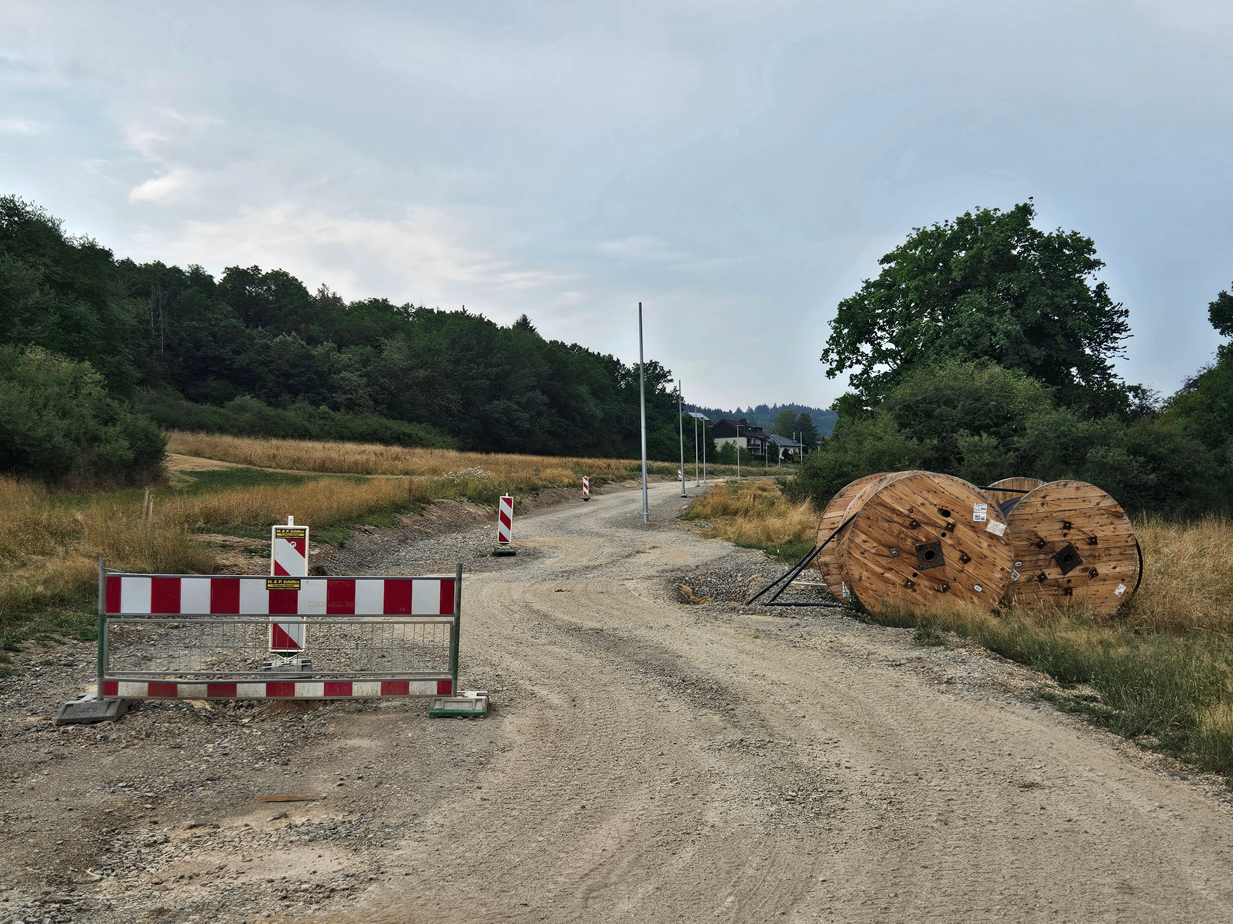 Das Foto zeigt die Baustraße, einige Warnbaken und Rollen mit Kabelleitungen.