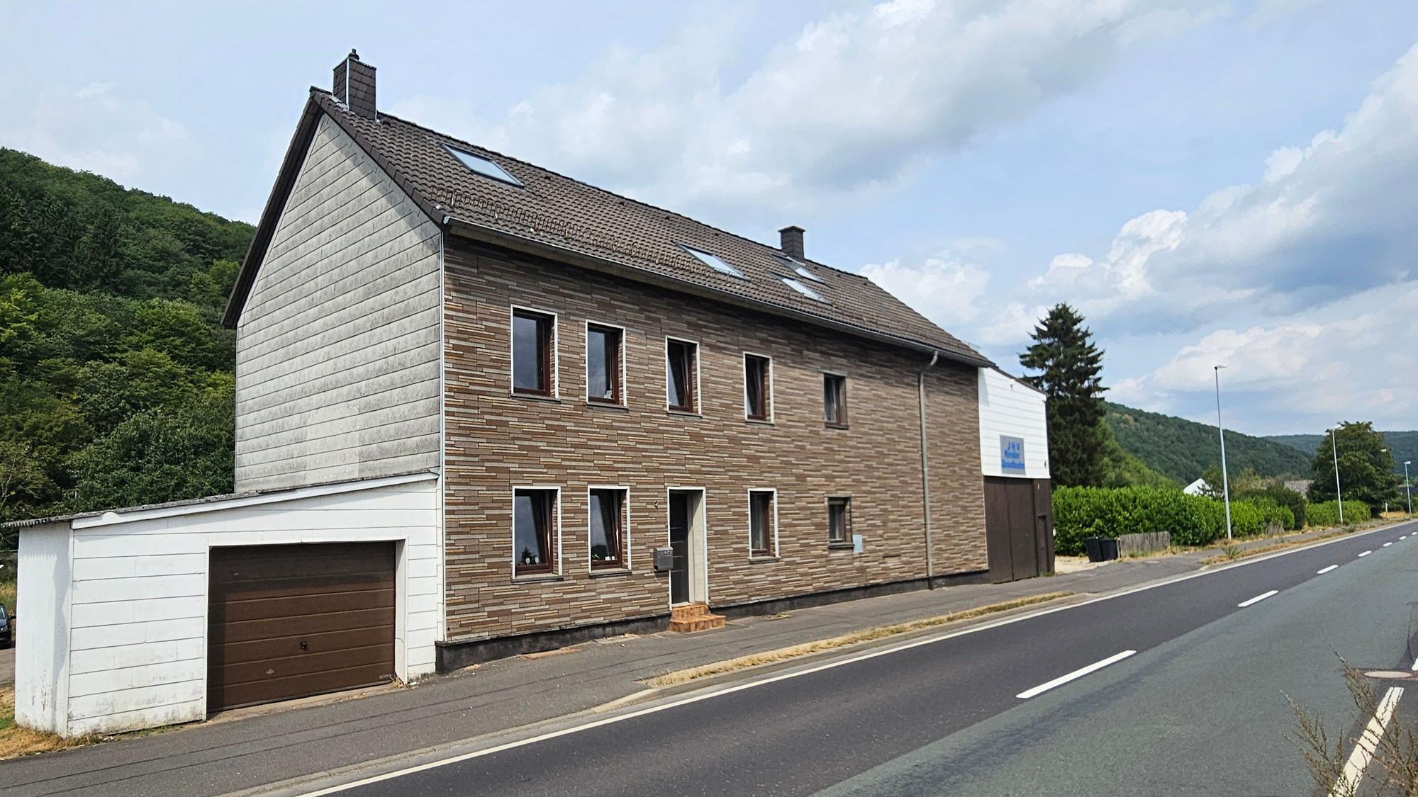 Das Foto zeigt ein zweigeschossiges Gebäude mit Garage und Scheune.