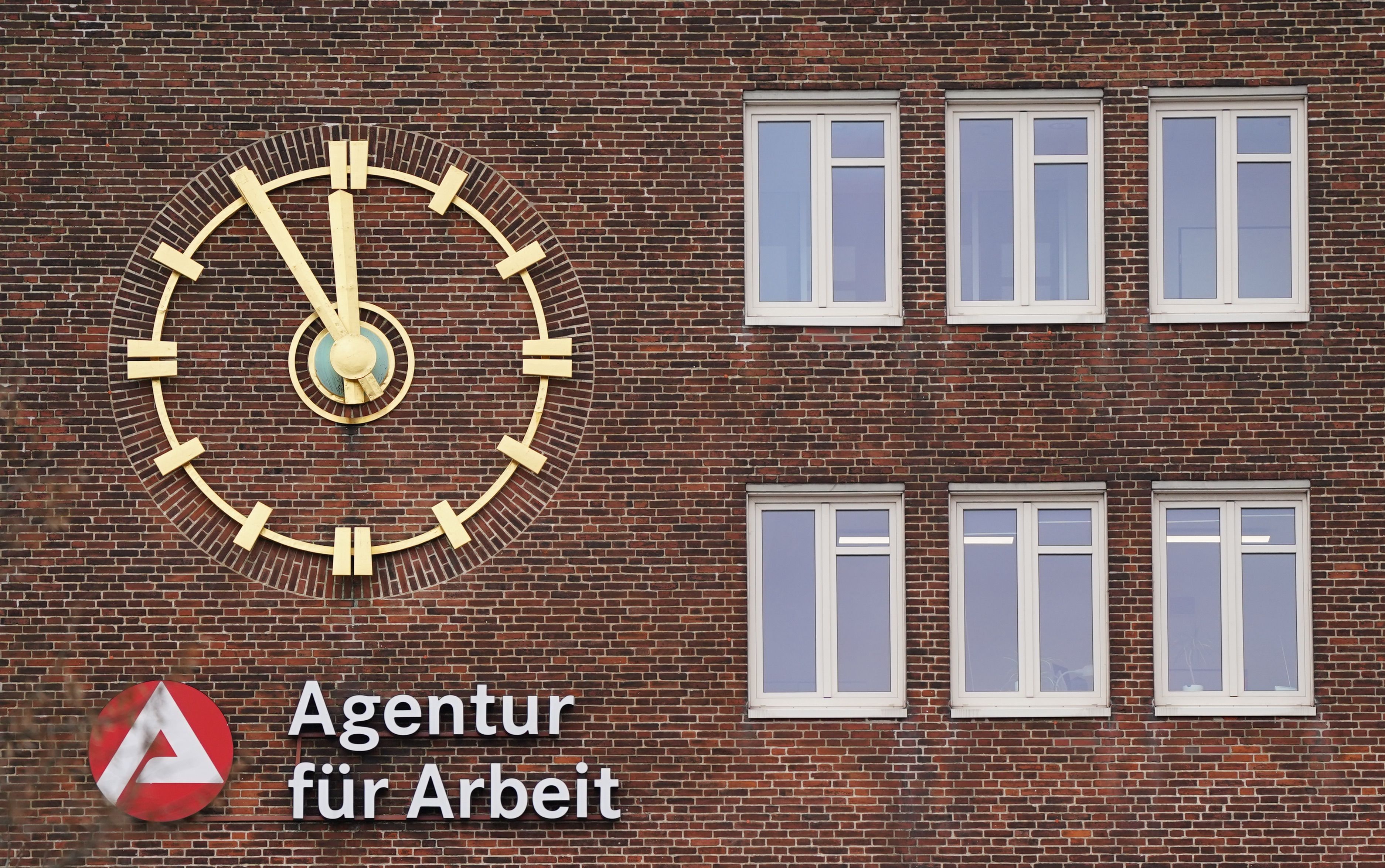 Die Uhr an der Fassade der Agentur für Arbeit zeigt fünf Minuten vor Zwölf an.