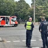 Zwei Polizisten stehen am Bahnübergang, dahinter ein Rettungswagen. Ein Unfallaufnahmeteam der Polizei ist in Köln-Buchheim vor Ort.