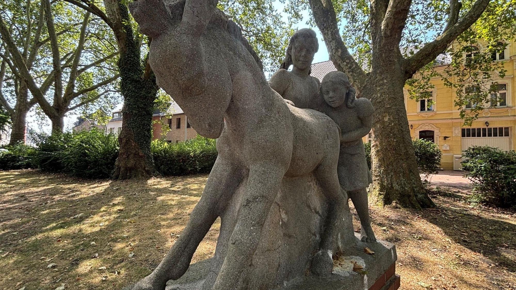 Zu sehen ist eine Skulptur zweier Mädchen mit einem Esel.