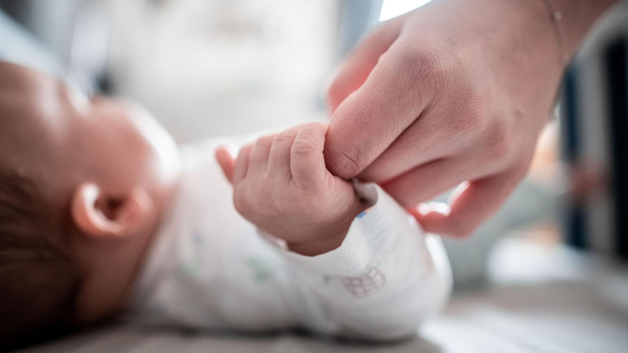 Ein Baby klammert sich an den Finger seiner Mutter. (Symbolbild)