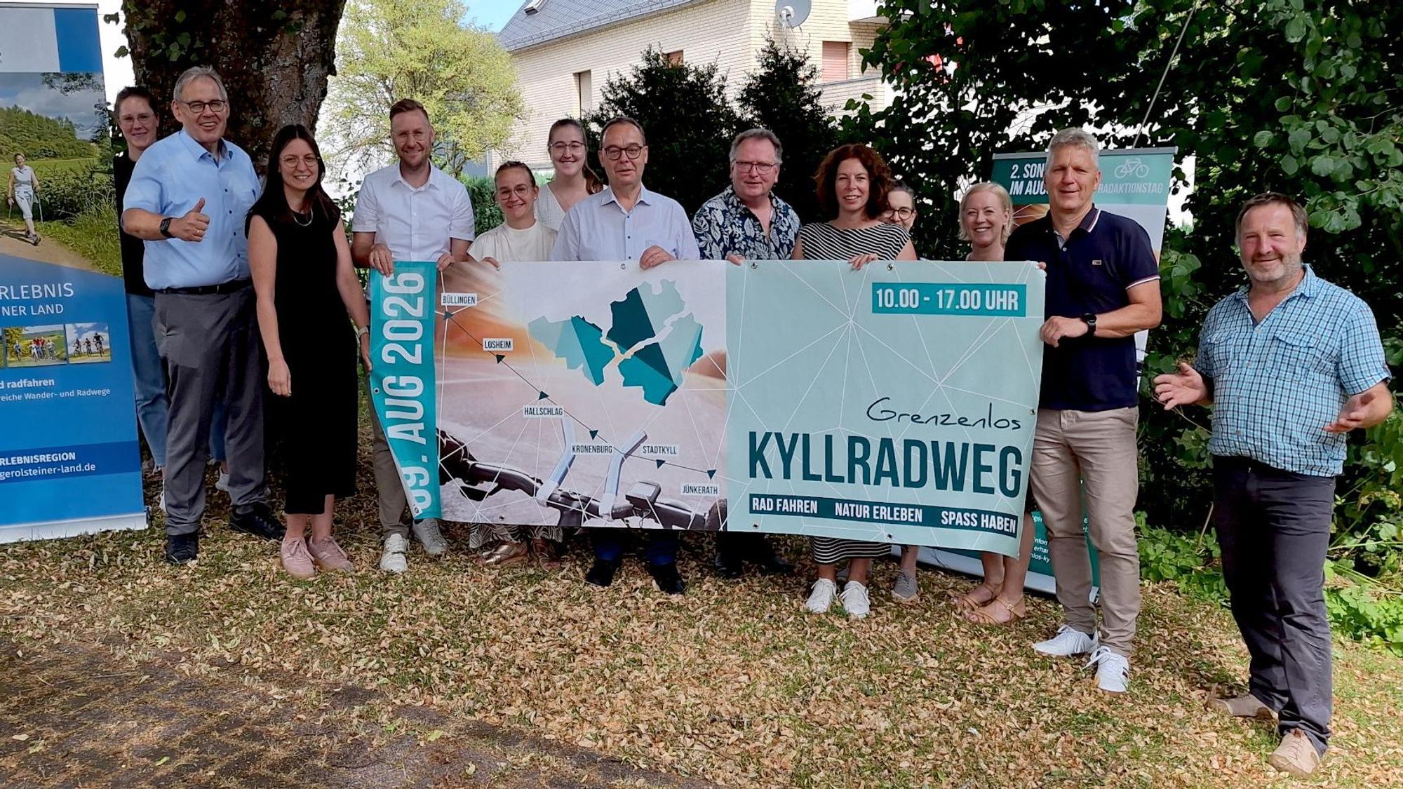 Die Genannten halten ein großes Banner mit der Aufschrift: „Kyllradweg“ in die Kamera.