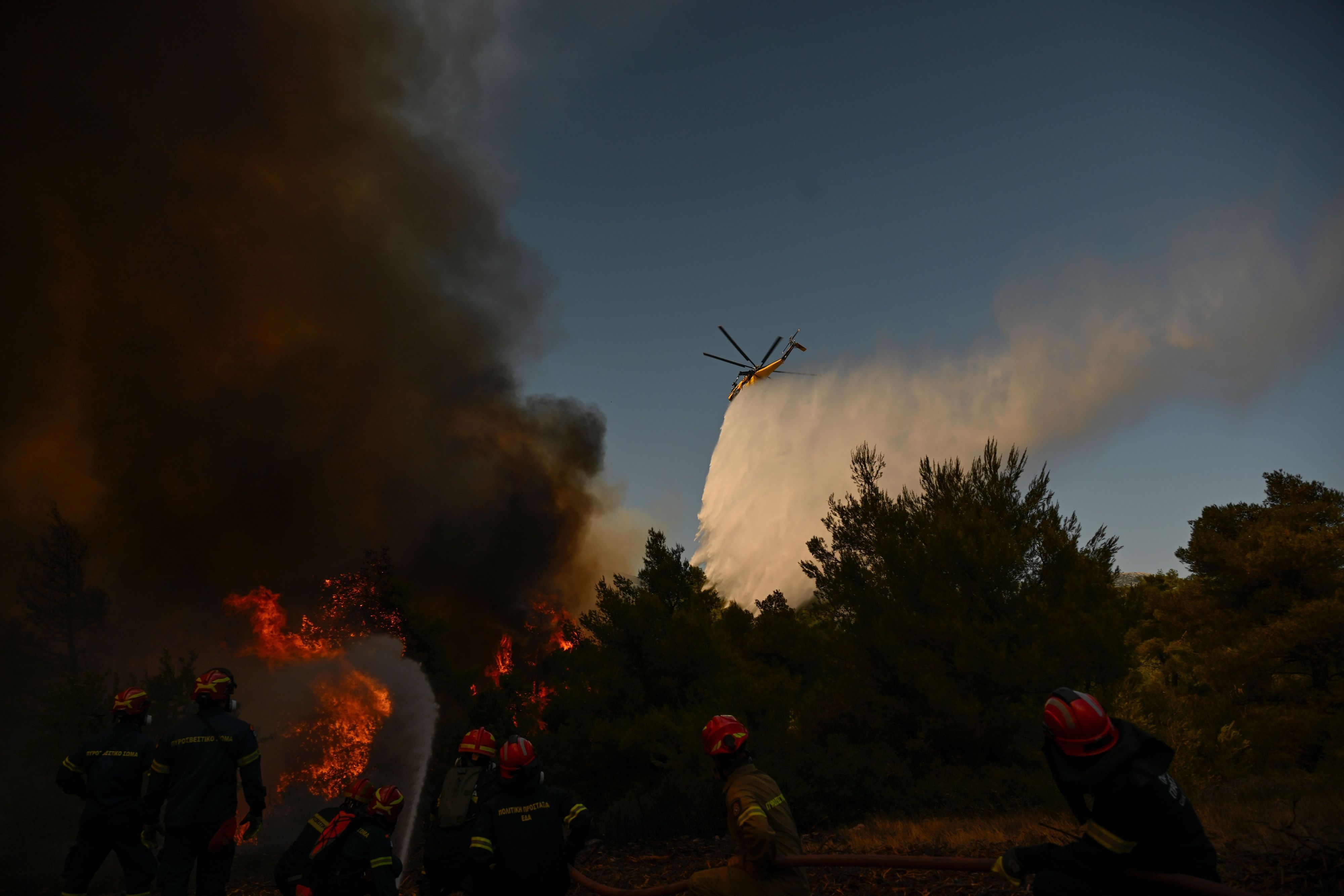 Ein Löschhubschrauber wirft bei einem Waldbrand in der Nähe von Porto Germeno nordwestlich von Athen Löschmittel über einen rauchverhangenen Wald ab.