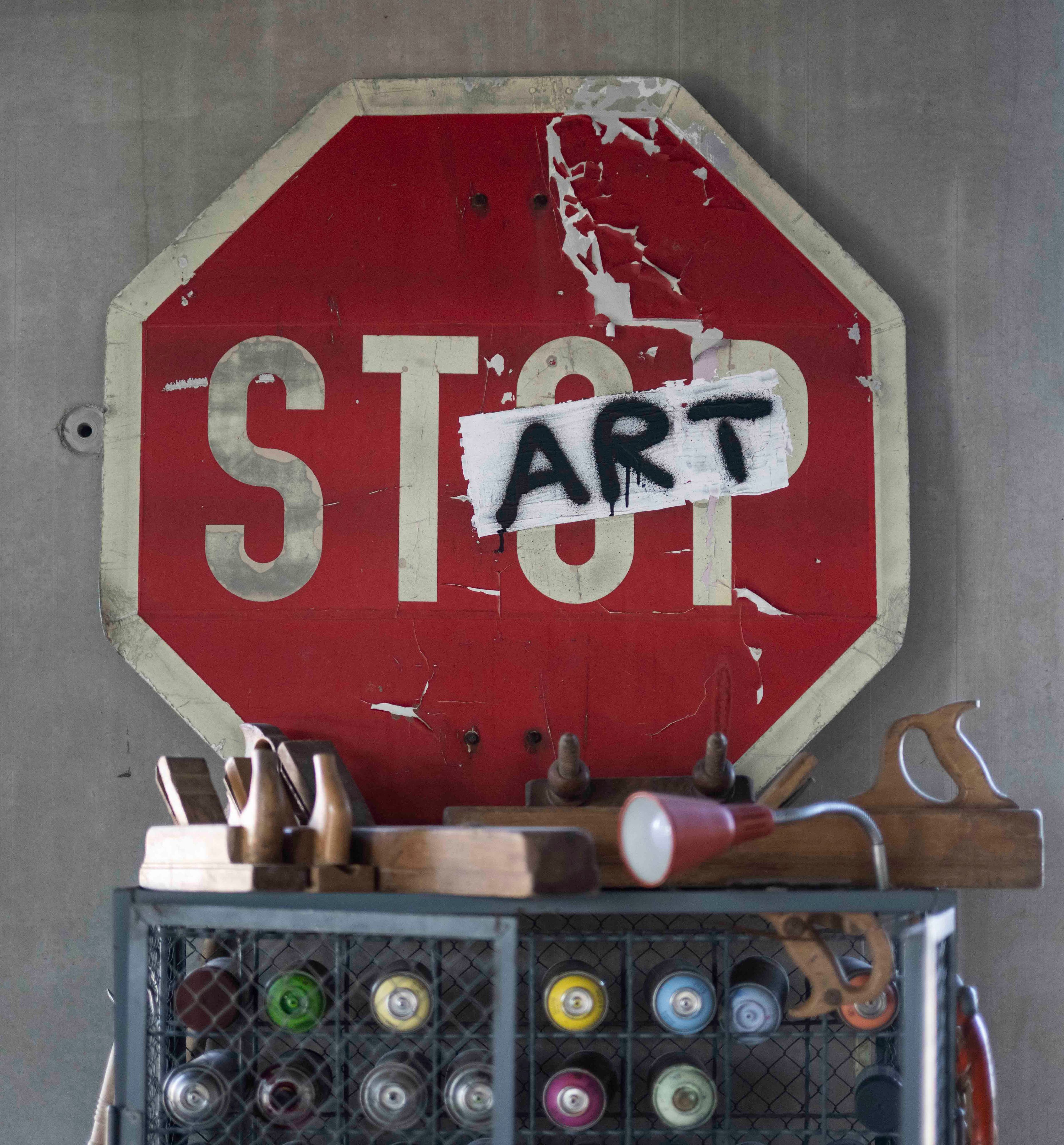 Auf einem roten Schild mit der Aufschrift Stop sind das o und das p mit einem Aufkleber überklebt, auf den art steht.