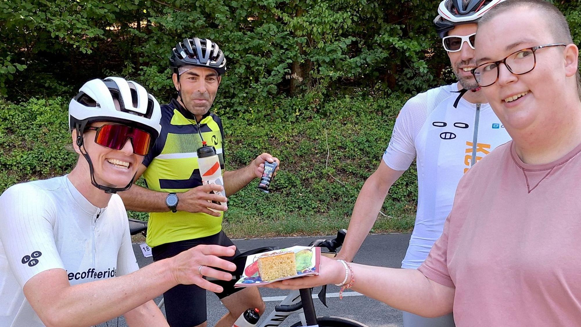 Demmer greift nach einem Stück Kuchen. Andere Radsportler schauen zu.
