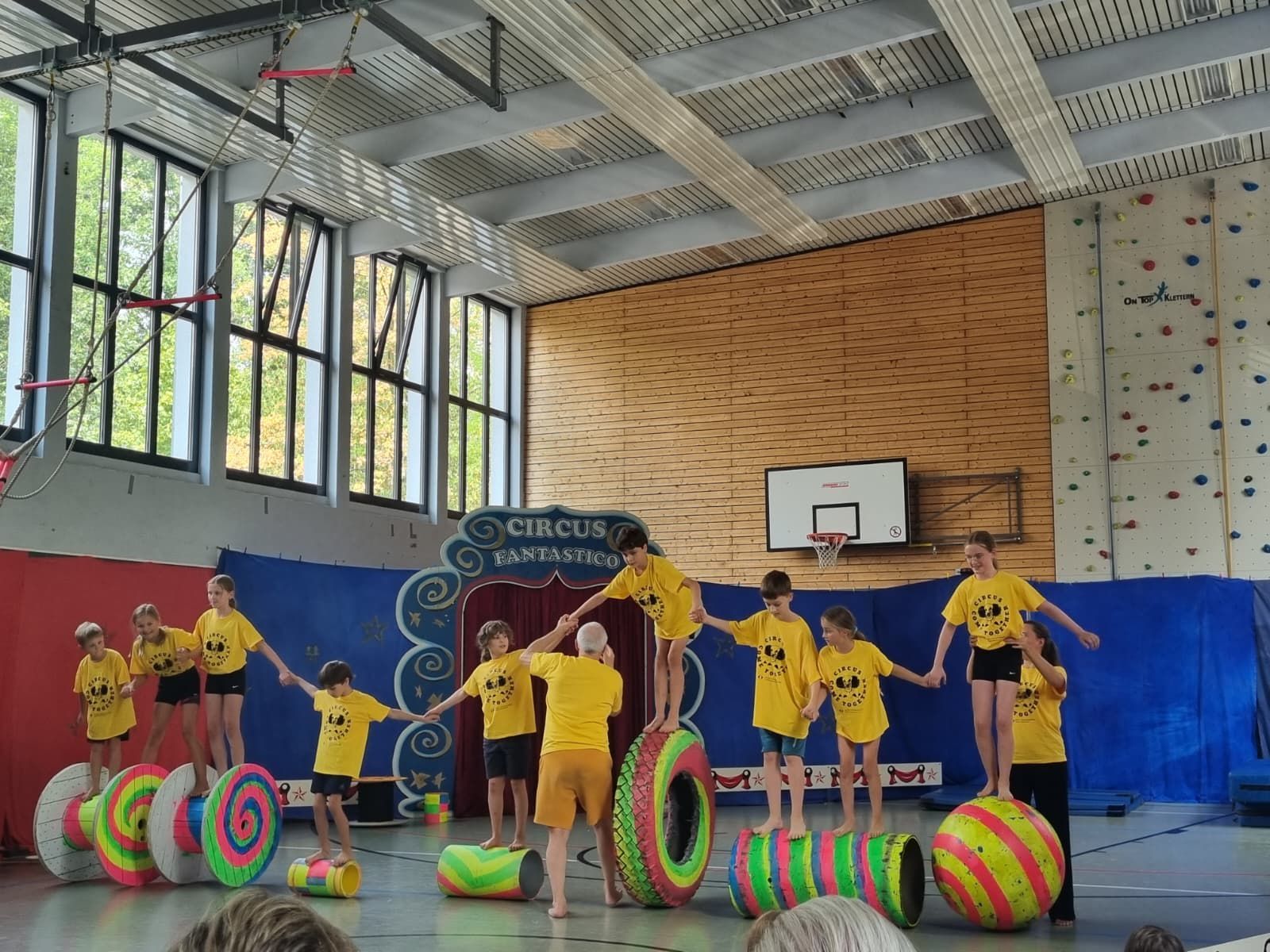 Kinder balancieren in einer Halle auf Rollen, Reifen und Bällen.