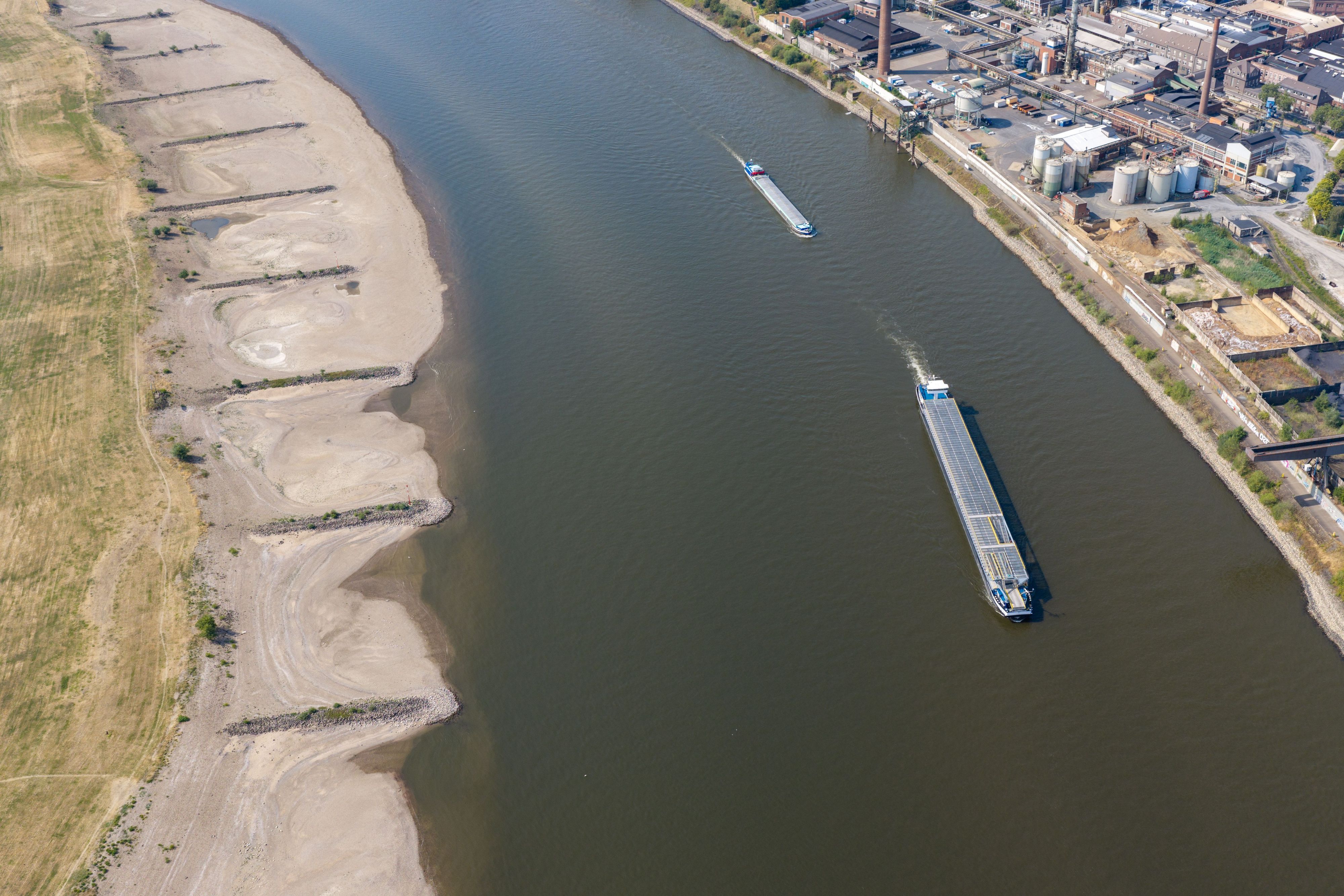 ARCHIV - 30.07.2026, Nordrhein-Westfalen, Duisburg: Am Rhein in Duisburg fahren Schiffe in der Fahrrinne, am Ufer sind breite Sandbänke sichtbar, die bei normalem Wasserstand unter Wasser sind. (Luftaufnahme mit einer Drohne) (zu dpa: «Minister: Krisenstab soll sich um bedrohte Schifffahrt kümmern») Foto: Christoph Reichwein/dpa +++ dpa-Bildfunk +++