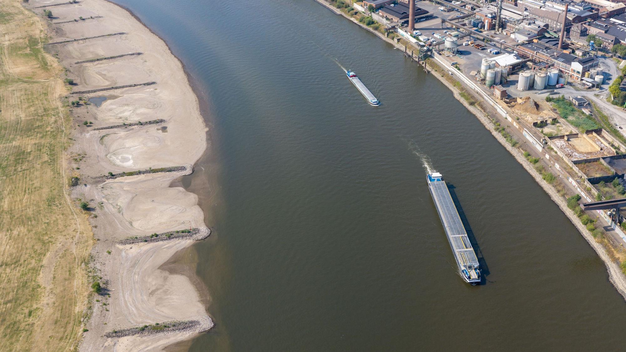 ARCHIV - 30.07.2026, Nordrhein-Westfalen, Duisburg: Am Rhein in Duisburg fahren Schiffe in der Fahrrinne, am Ufer sind breite Sandbänke sichtbar, die bei normalem Wasserstand unter Wasser sind. (Luftaufnahme mit einer Drohne) (zu dpa: «Minister: Krisenstab soll sich um bedrohte Schifffahrt kümmern») Foto: Christoph Reichwein/dpa +++ dpa-Bildfunk +++