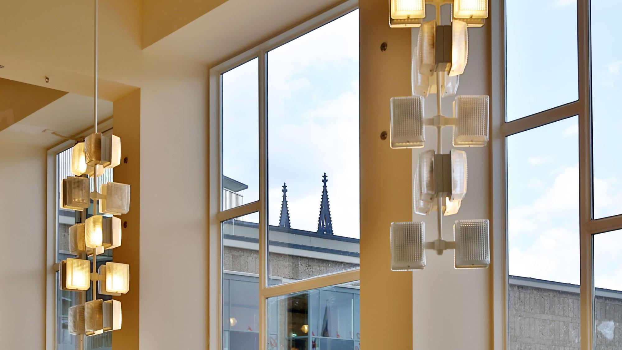 Durch ein Fenster sind die Turmspitzen einer Kirche zu erkennen.