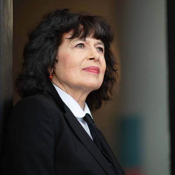 Eine Frau blickt ernst an der Kamera vorbei.