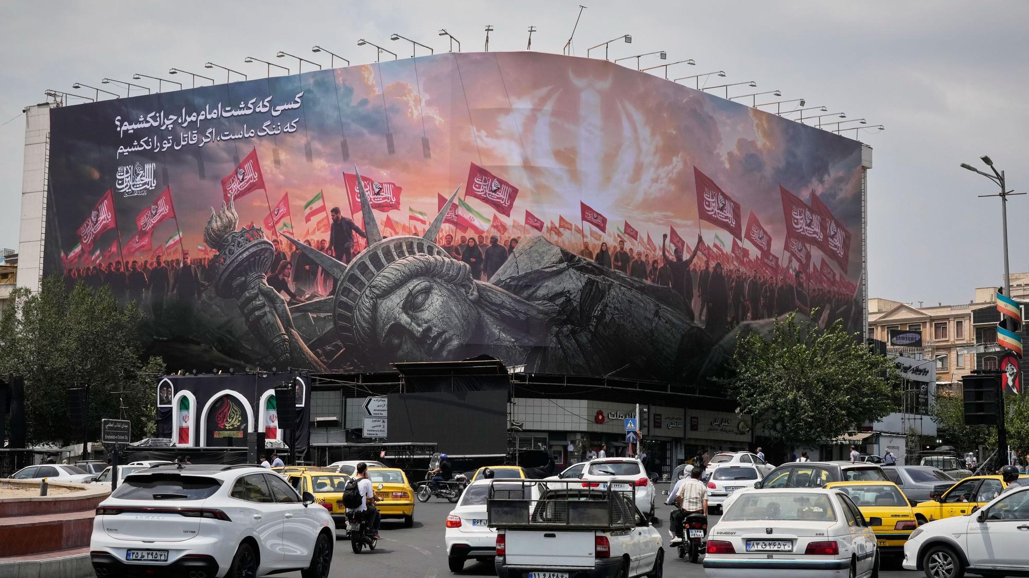 Teheran: Eine Plakatwand, auf der eine umgestürzte Freiheitsstatue und Menschenmengen mit iranischen und schiitischen Flaggen zu sehen sind.