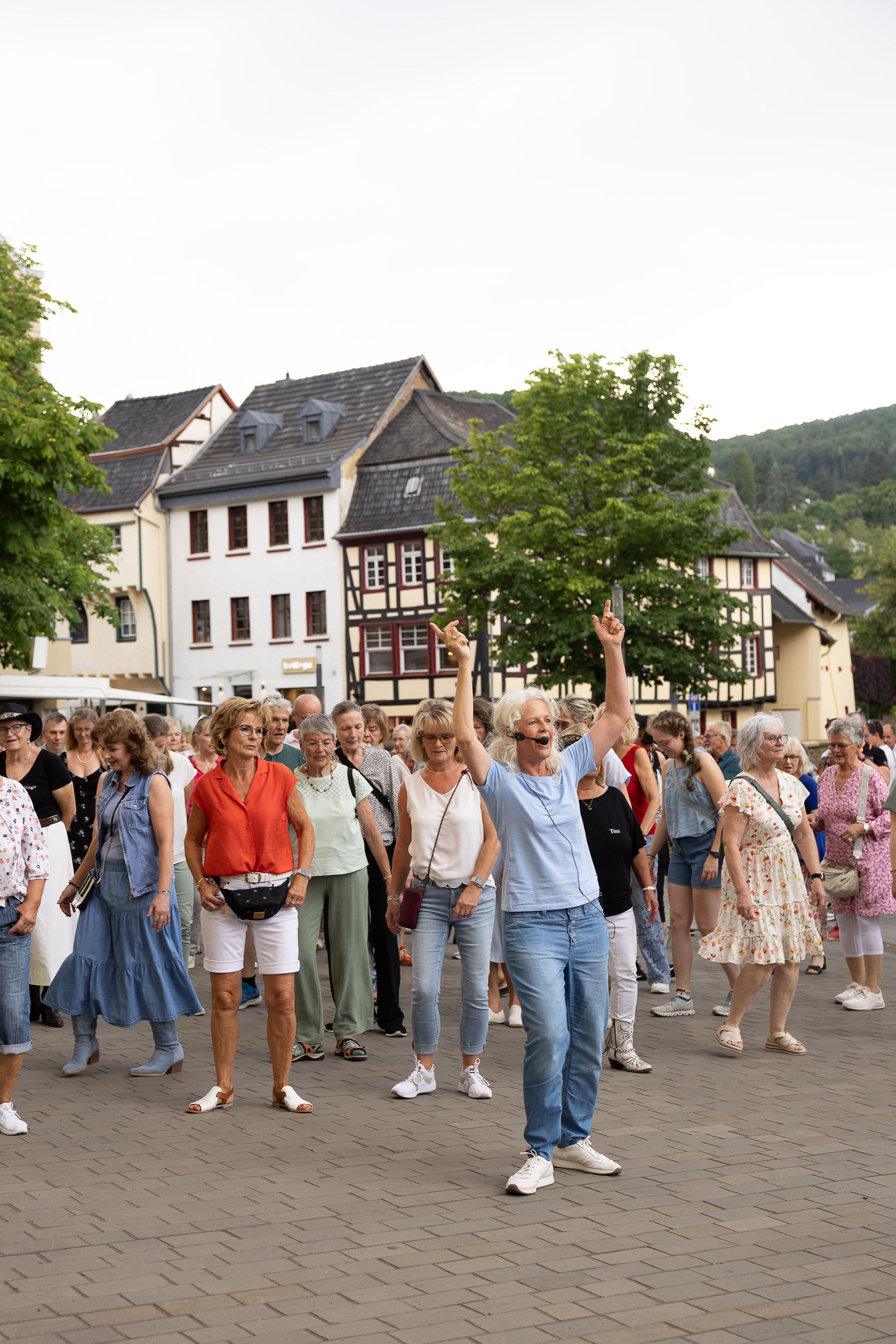 Die Tanzlehrerin hat beide Arme erhoben. Dahinter stehen mehrere Frauen.