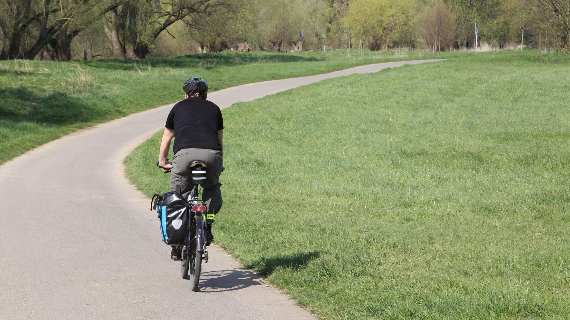 Ein Mann mit seinem Fahrrad auf einem Fahrradweg.