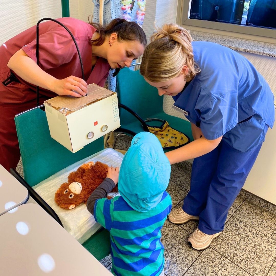 ein Kind lässt seinen Kuscheltier-Affen in der Teddyklinik untersuchen