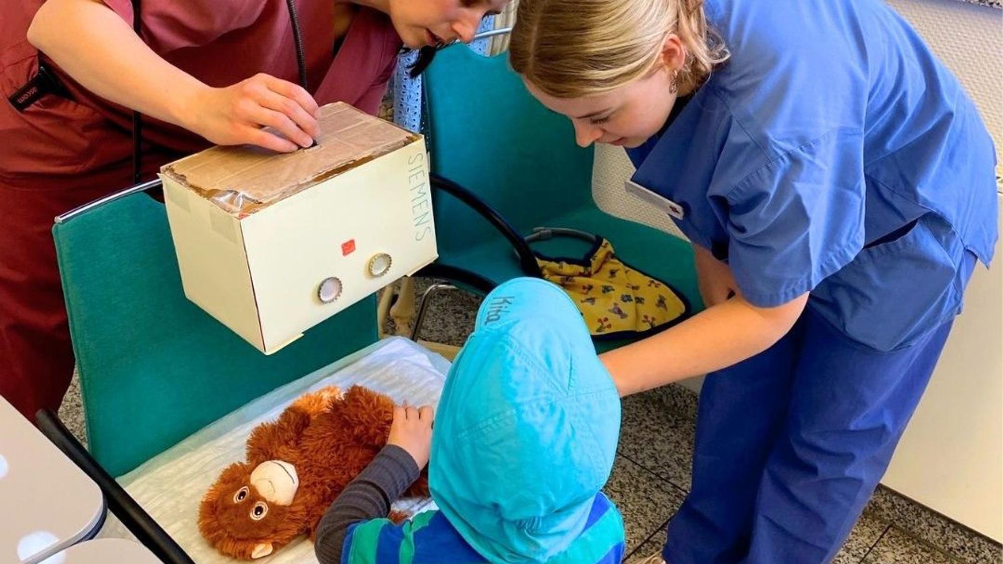 ein Kind lässt seinen Kuscheltier-Affen in der Teddyklinik untersuchen