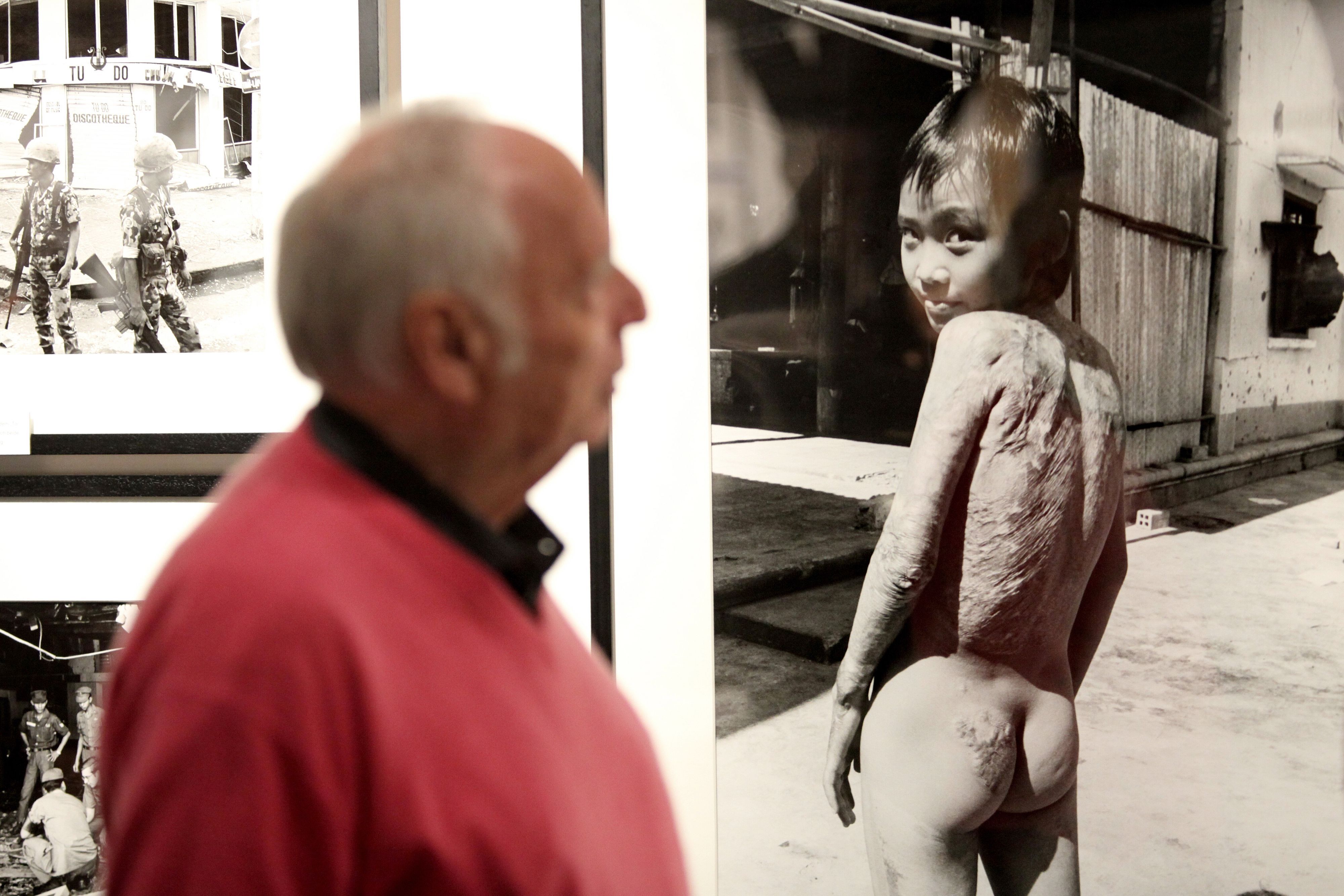 Der Kriegsfotograf Perry Kretz steht bei der Ausstellung „Augen auf und durch!“ im Stadtmuseum Schleswig neben dem berühmten Foto von Kim Phuc, das die damals neunjährige Vietnamesin nach dem Napalm-Angriff im Vietnamkrieg zeigt.
