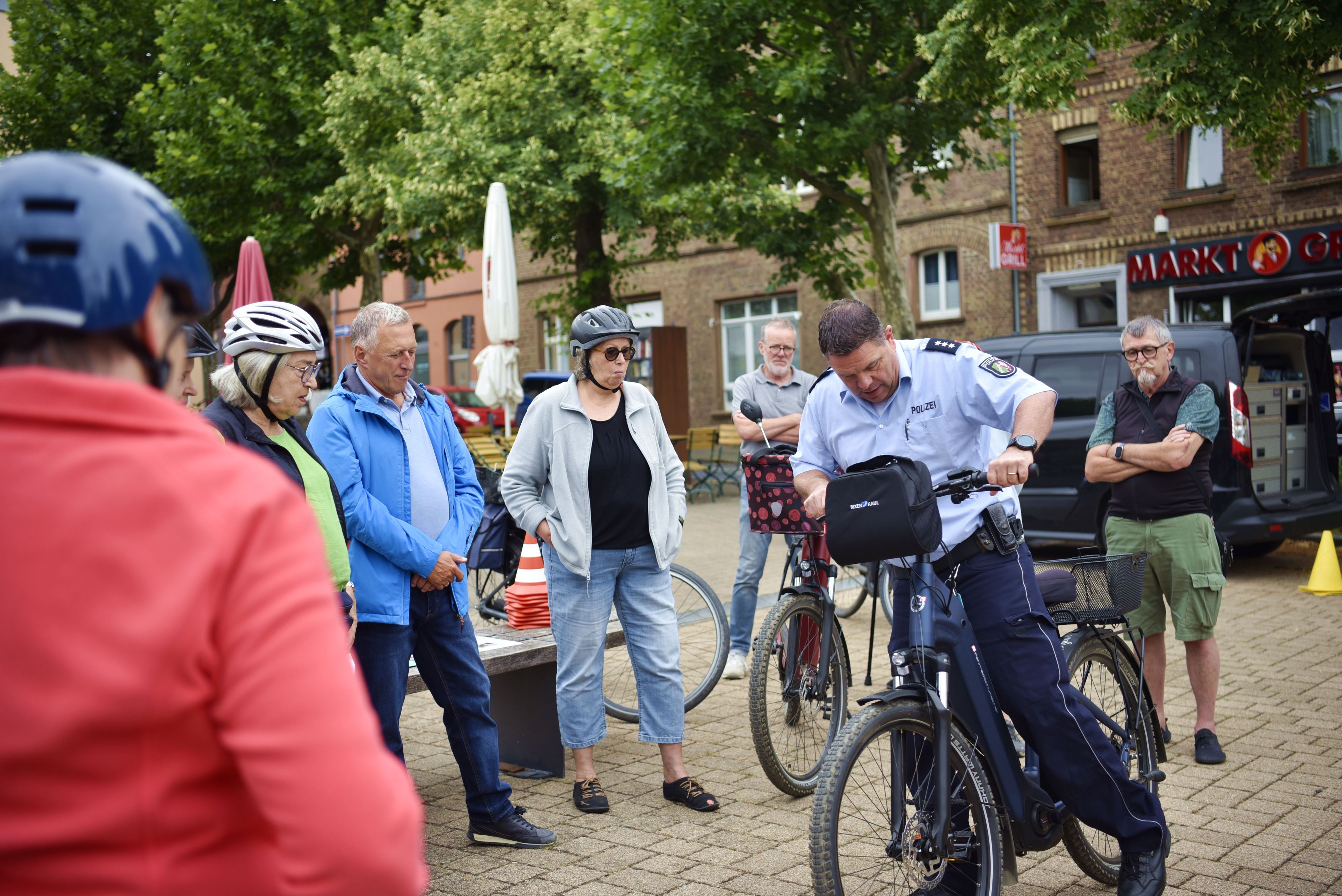 Ein Polizist steigt umringt von Menschen mit Fahrradhelmen auf ein Pedelc.