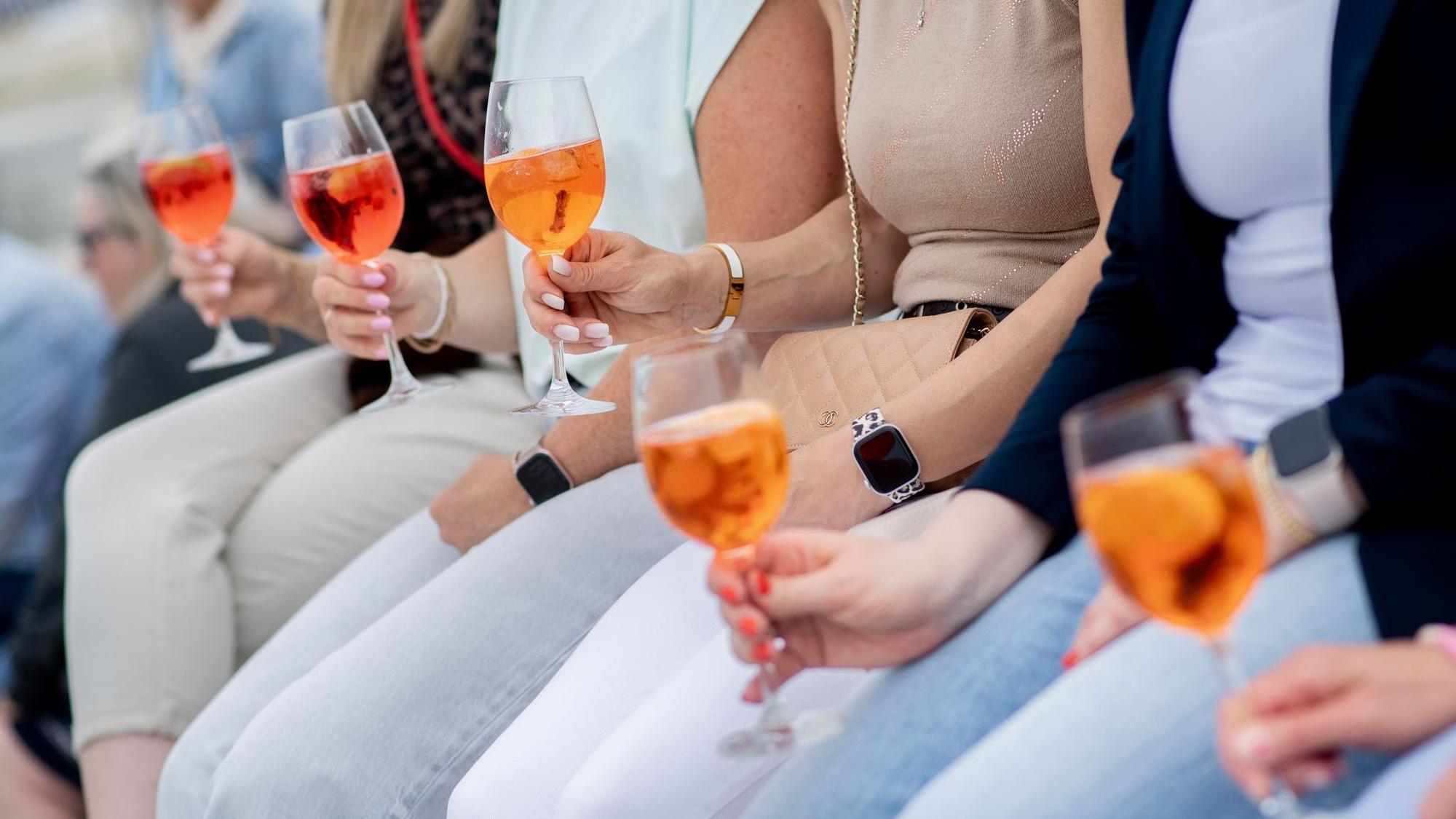 Aperol Spritz in den Händen von Personen.