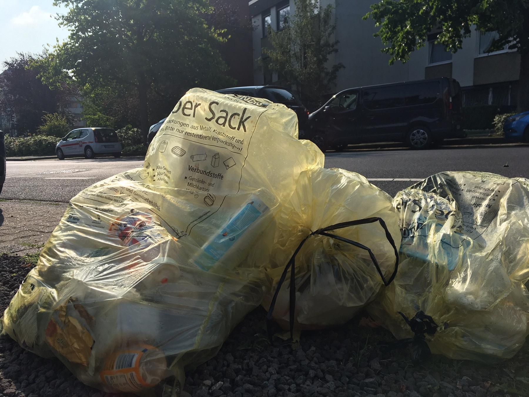 Gelbe Säcke mit Verpackungsmüll liegen am Straßenrand.