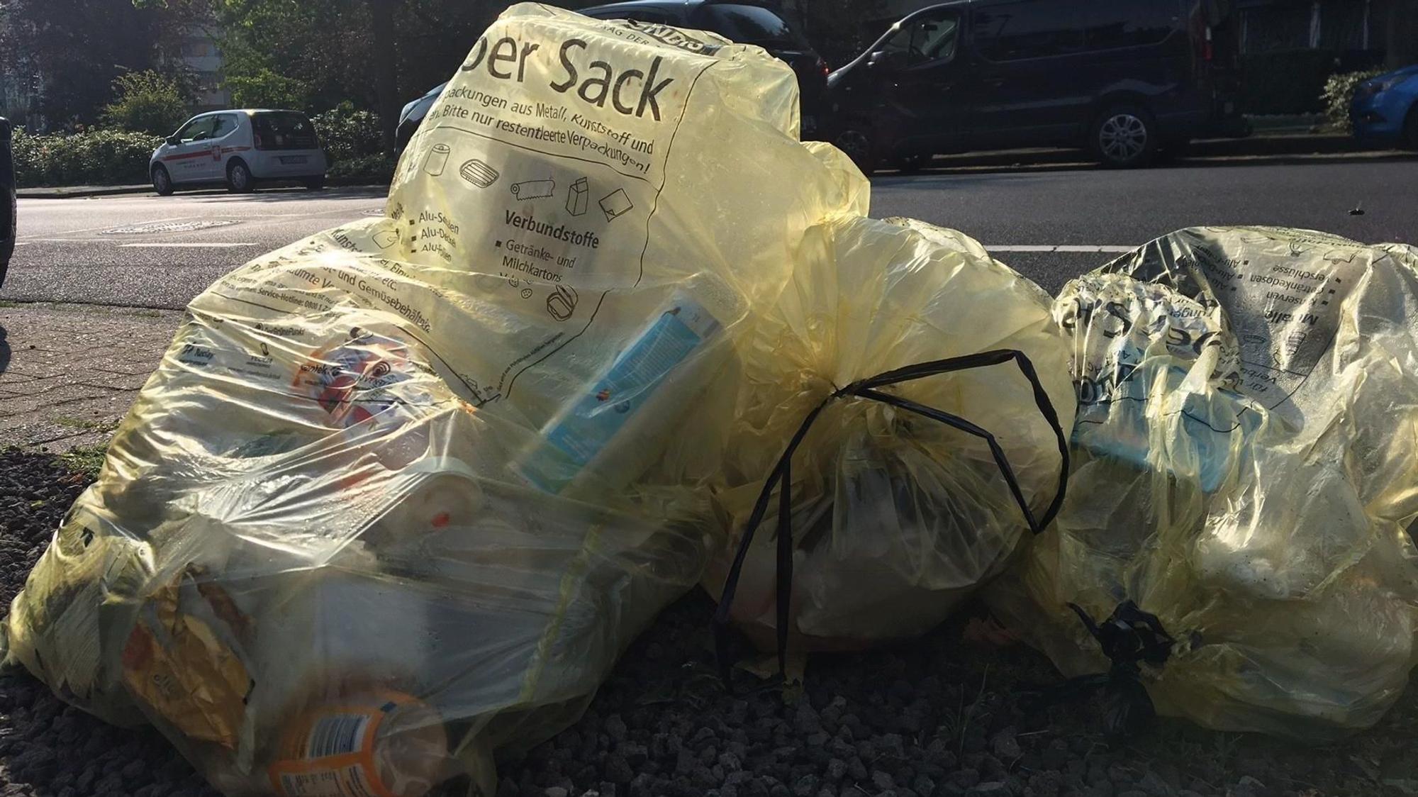 Gelbe Säcke mit Verpackungsmüll liegen am Straßenrand.