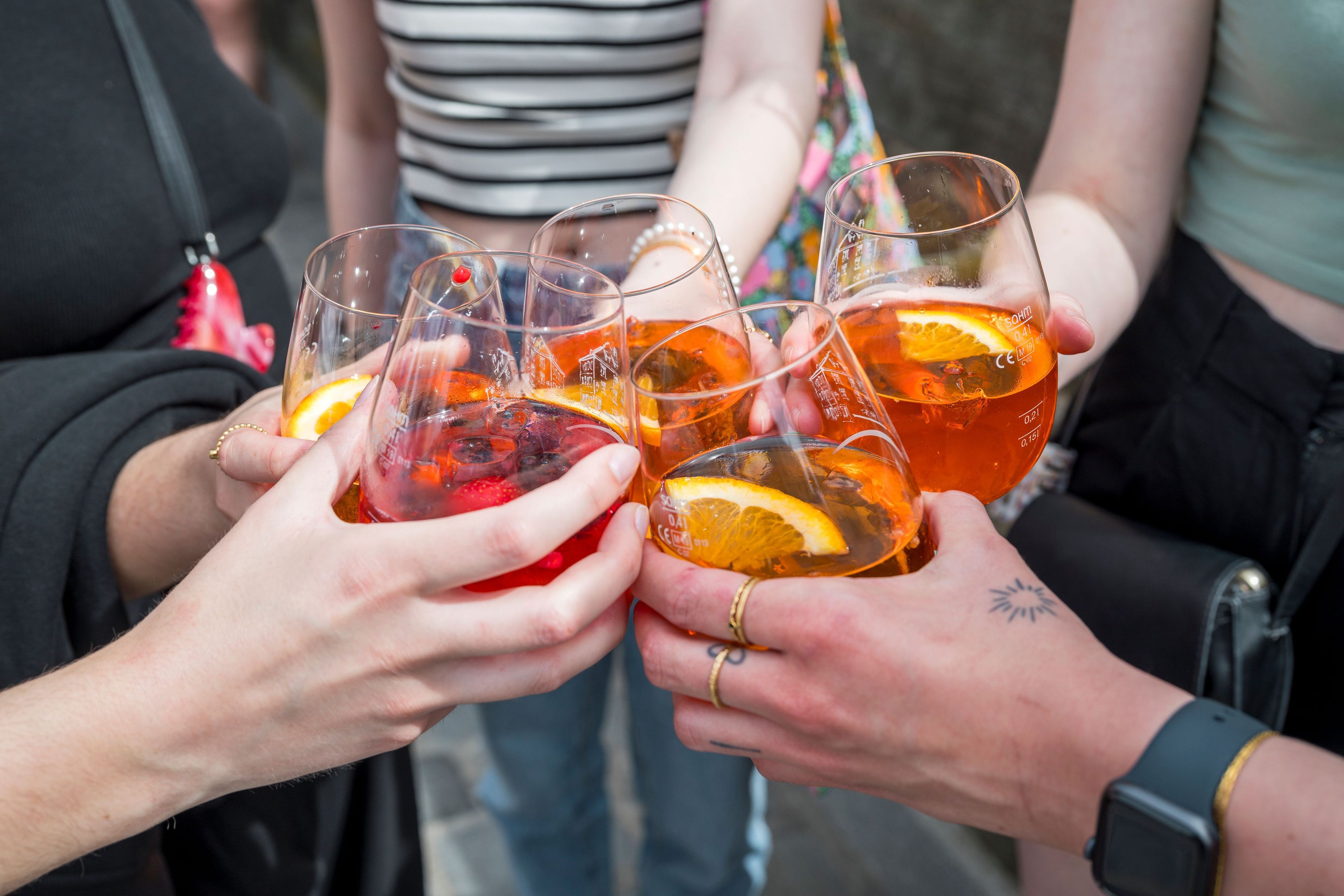 Fünf Personen stoßen mit ihren Gläsern mit Aperol Spritz an.