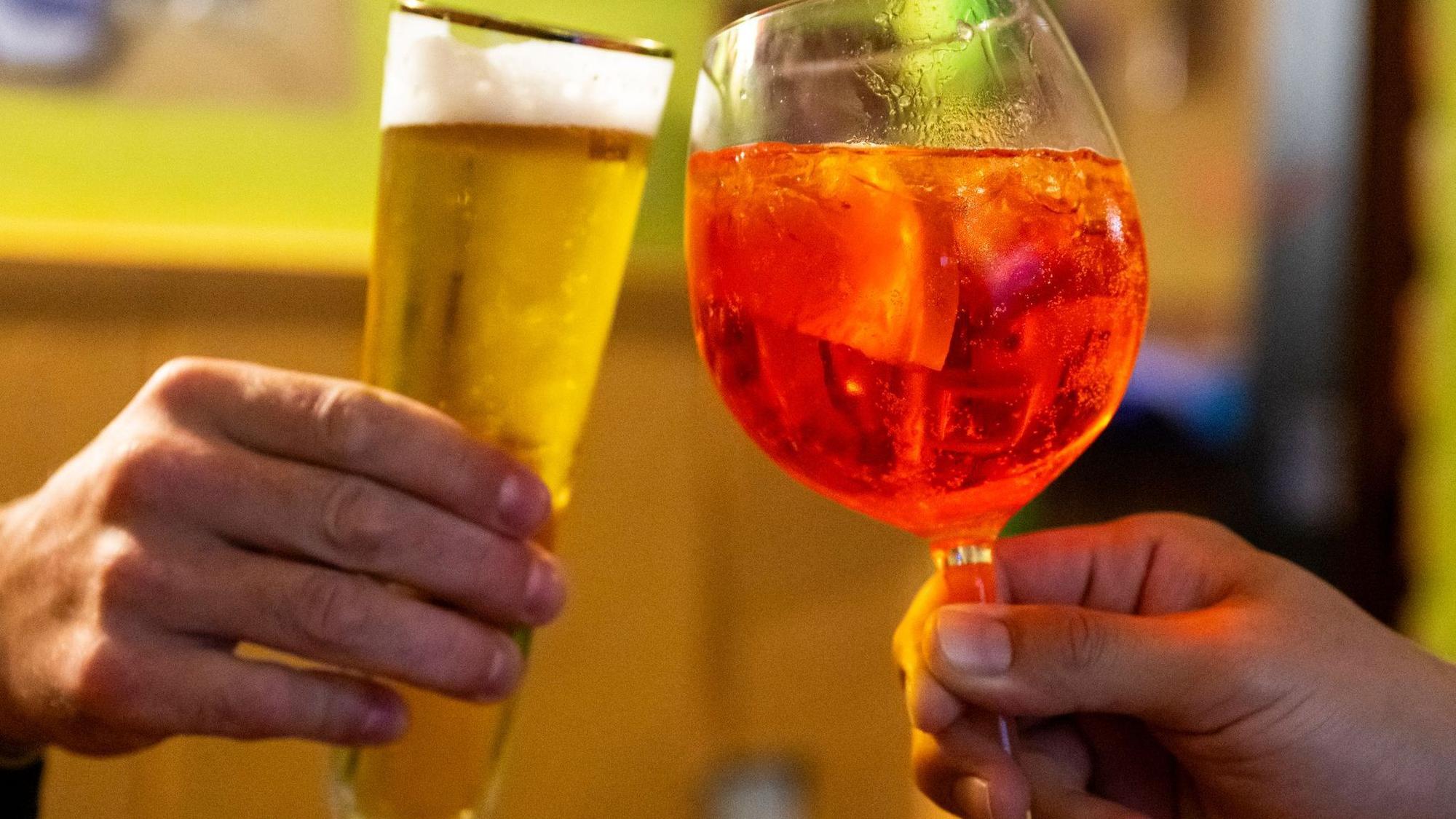 Aperol Spritz und ein Bierglas beim Prosten.
