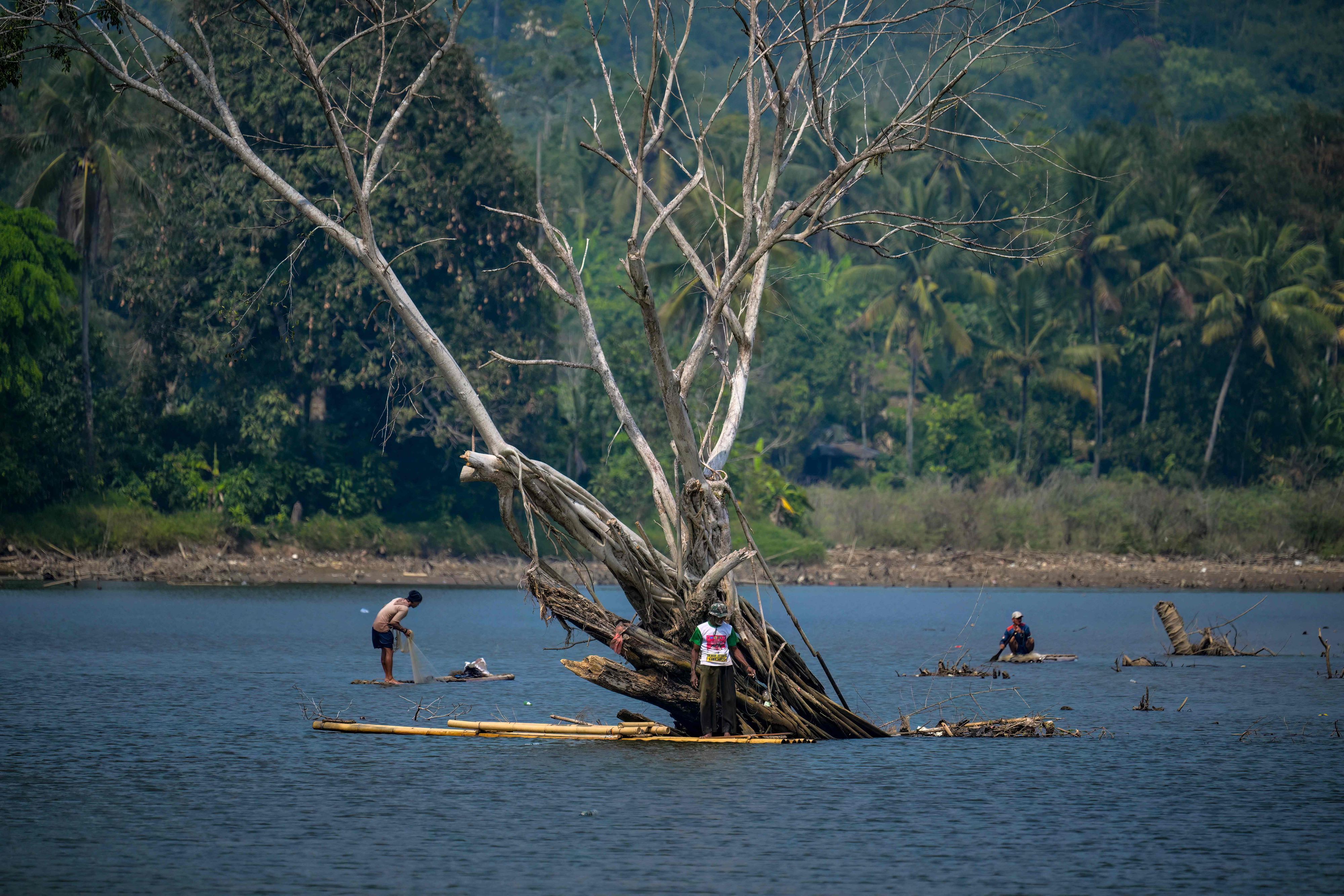 Drei Männer fischen im Juli 2026 auf einem Bambusfloß auf einem ausgetrockneten See nahe dem Dorf Somang in Indonesien.
