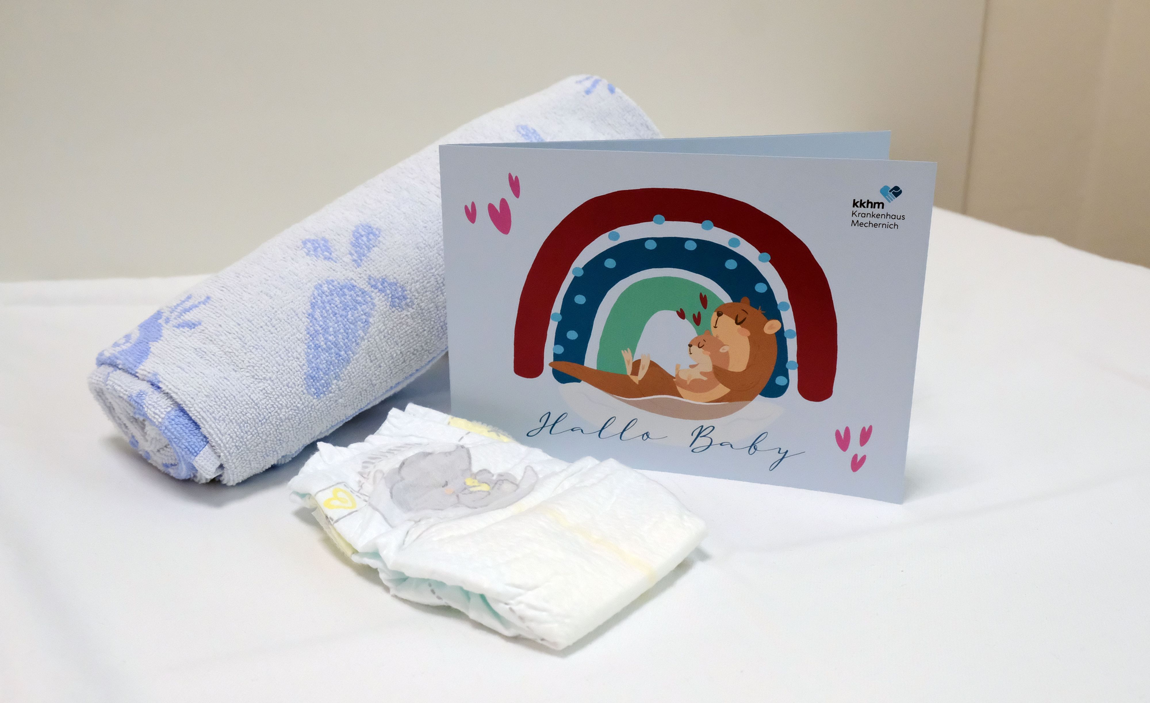 Ein zusammengerolltes Handtuch, eine Windel und eine Glückwunschkarte mit der Aufschrift „Hallo Baby“ im Mechernicher Kreißsaal.