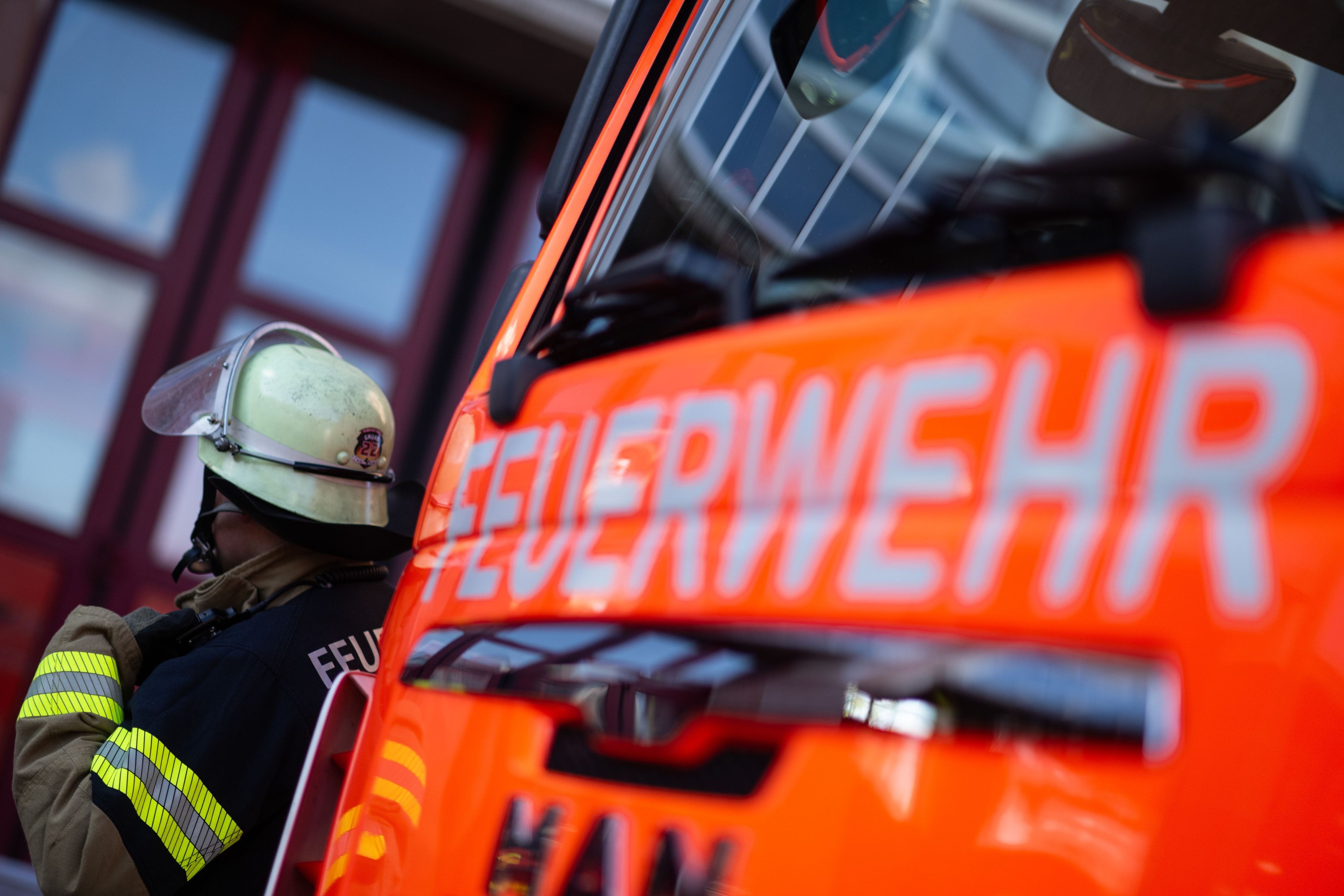 Eine Einsatzkraft der Feuerwehr steht neben einem Einsatzfahrzeug der Feuerwehr. (Symbolbild)