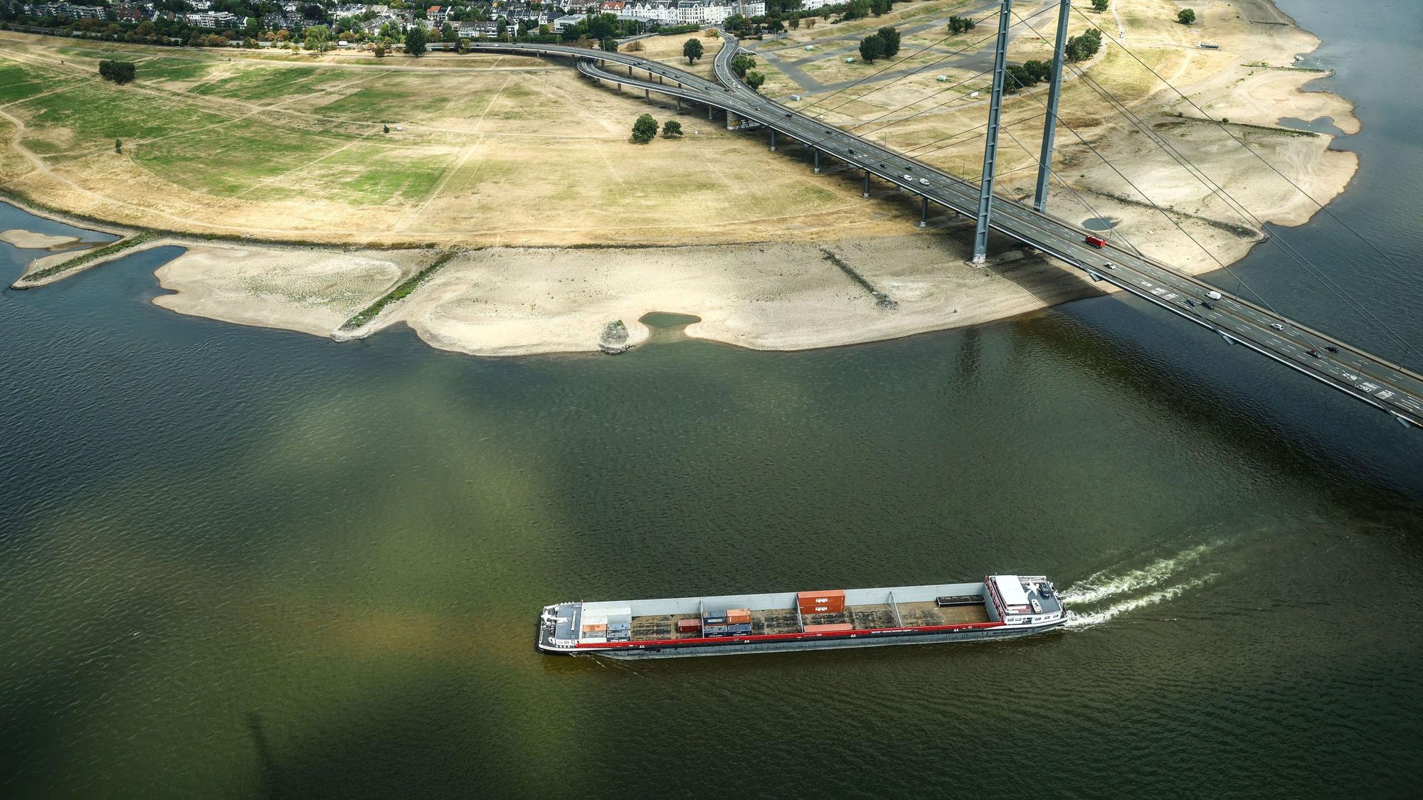 Ein Containerschiff fährt mit geringer Ladung bei Niedrigwasser am Rheinknie in Düsseldorf vorbei.
