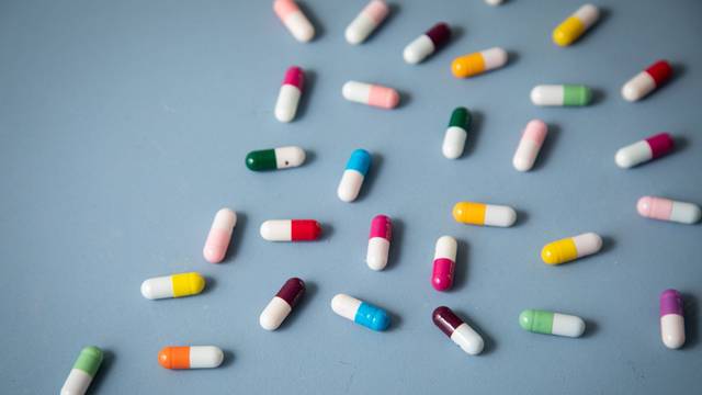 Unterschiedlich farbige Tabletten liegen auf einem Tisch.