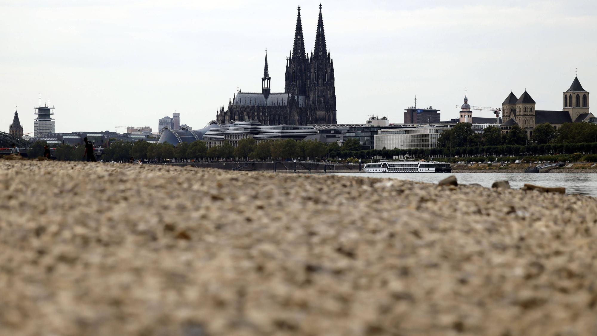Der Kölner Dom ragt über das ausgetrocknete Flussbett. Der Rheinpegel ist in Köln derzeit historisch niedrig.