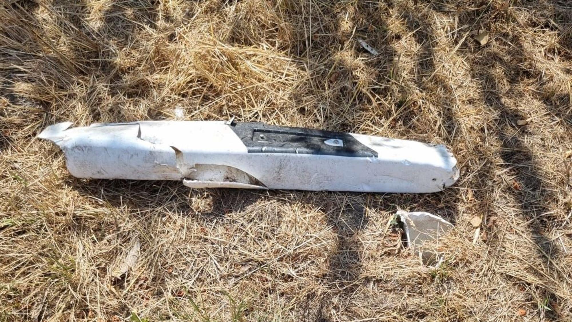 Ein zerstörter Leitpfosten liegt auf einer vertrockneten Wiese am Straßenrand.