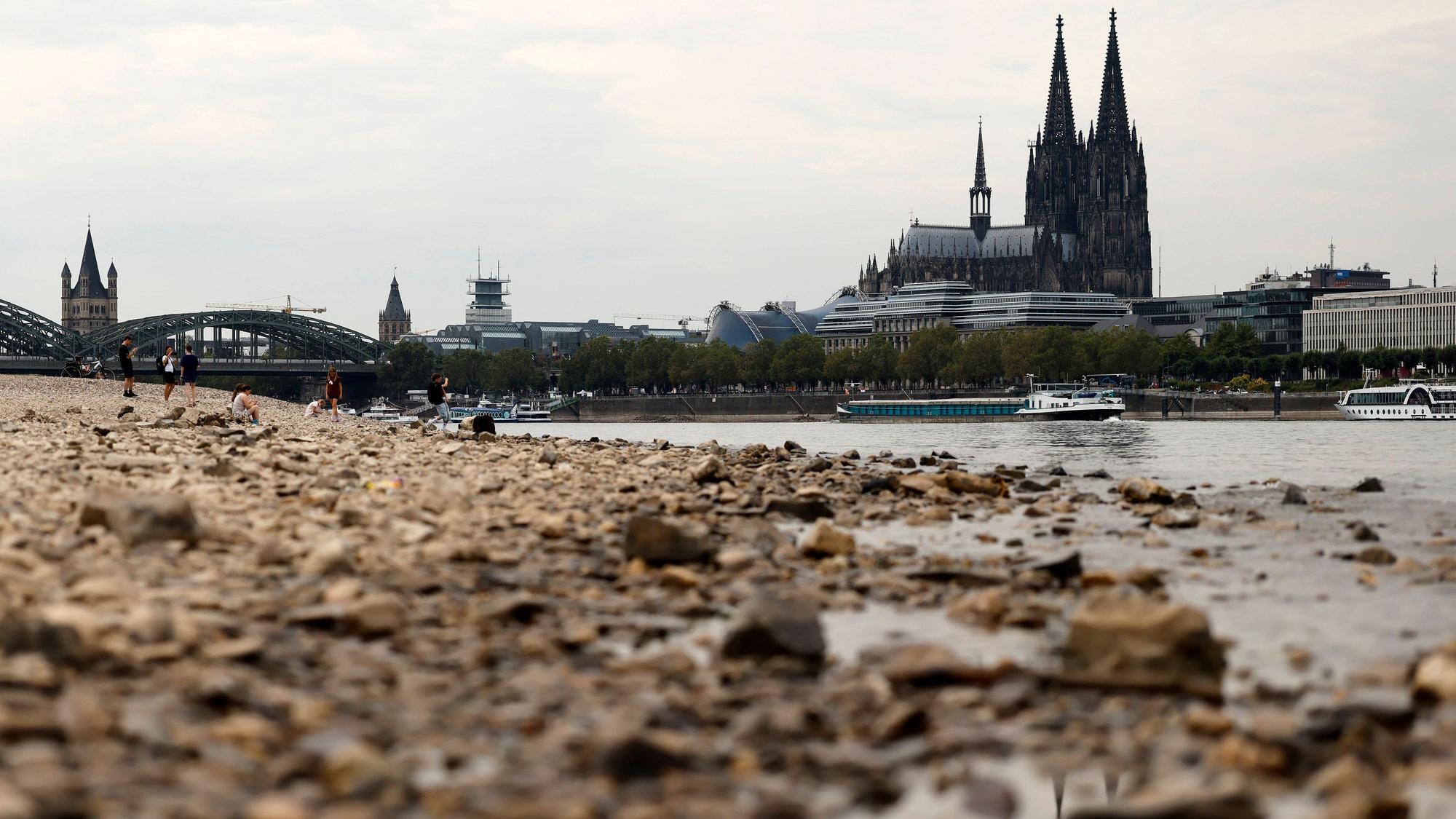 Spaziergänger stehen im ausgetrockneten Teil des Flussbett - im Hintergrund eine Rheinfähre und der Kölner Dom. Der Rheinpegel ist in Köln und Bonn auf einem Rekordtief. Viele Rheinwiesen sind verdorrt und versteppt und der sonst so stolze Fluss hat sich tief in sein Bett zurückgezogen, gibt den Blick auf trockene Ufer frei. Der Pegel lag am Wochenende mit 67 cm so tief wie noch nie seit der Messung. Themenbild, Symbolbild Köln, 29.07.2026 NRW Deutschland *** Walkers stand in the dried-up part of the riverbed in the background, a Rhine ferry and Cologne Cathedral. The Rhines water level in Cologne and Bonn is at a record low. Many Rhine meadows have withered and turned into scrubland, and the riverusually so mightyhas receded de Copyright: xChristophxHardtx