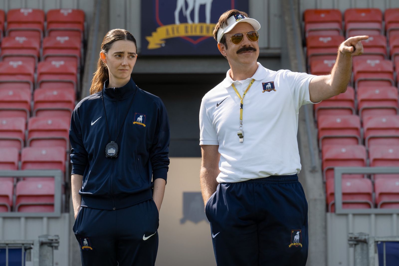 Ted Lasso (Jason Sudeikis) ist zurück: Dass ausgerechnet ein Mann die Lady Greyhounds trainiert, findet Alice Chilton(Tanya Reynolds) allerdings nicht so prickelnd. (Bild: © Apple TV / Collin Hutton)