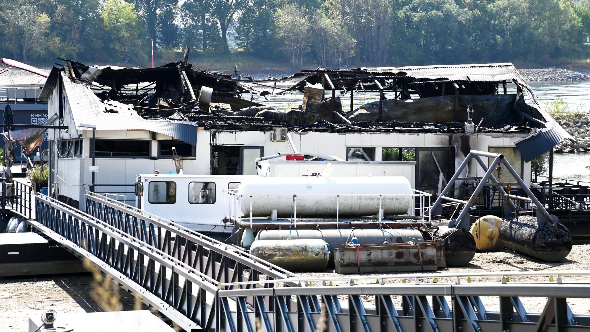 Ein Tag nach dem Brand auf dem Sürther Bootshaus ist von dem Schiff nicht mehr viel übrig.