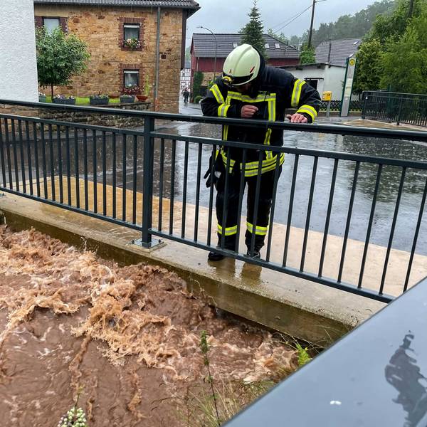 Das Bild zeigt einen Feuerwehrmann, der am 14. Juli 2021 einen Bach in Bad Münstereifel-Gilsdorf beobachtet.