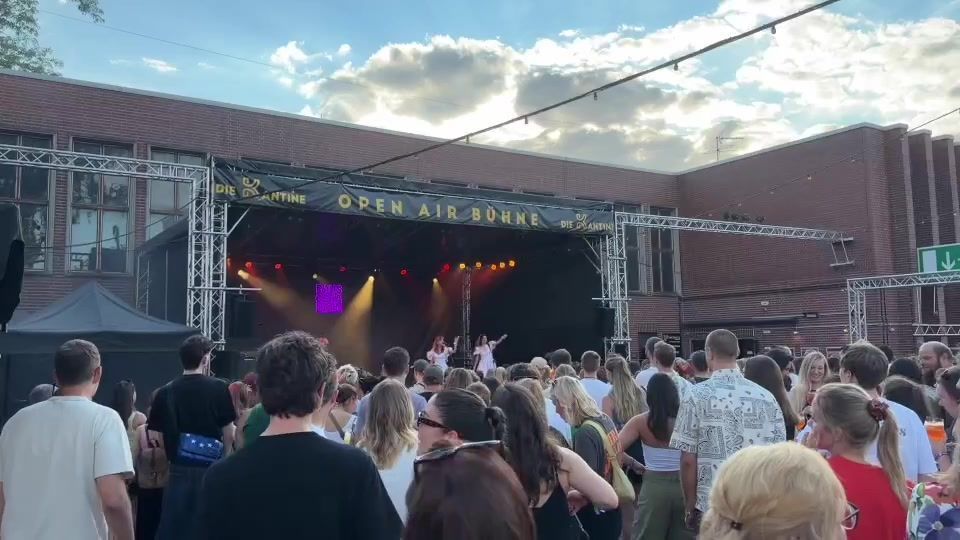 Eine Menschenmenge steht vor einer Open-Air-Bühne.
